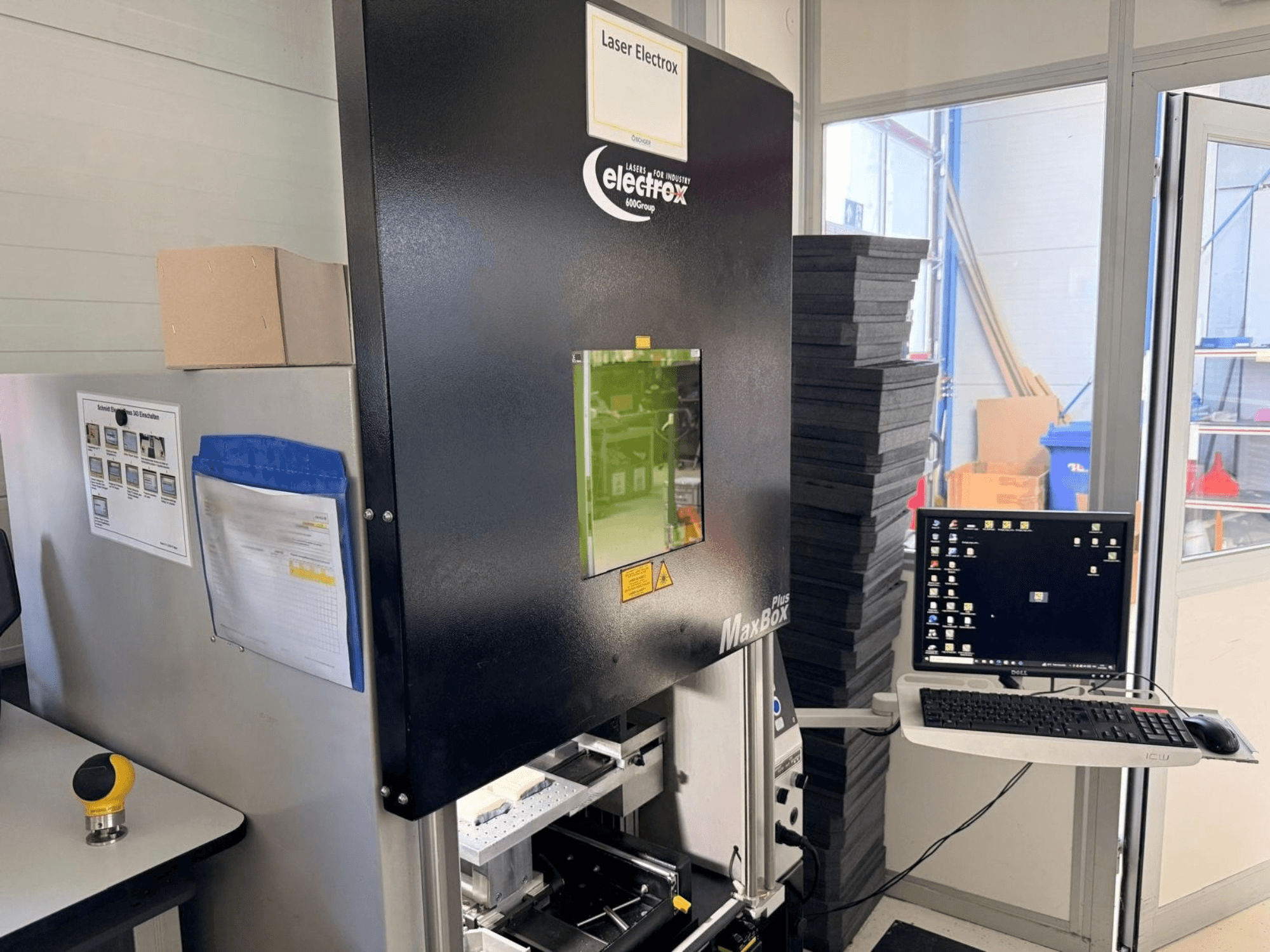 Máquina de marcação a laser ELECTROX MaxBox Plus numa vista lateral, apresentando um monitor de controlo, uma janela de visualização verde e uma área de trabalho.