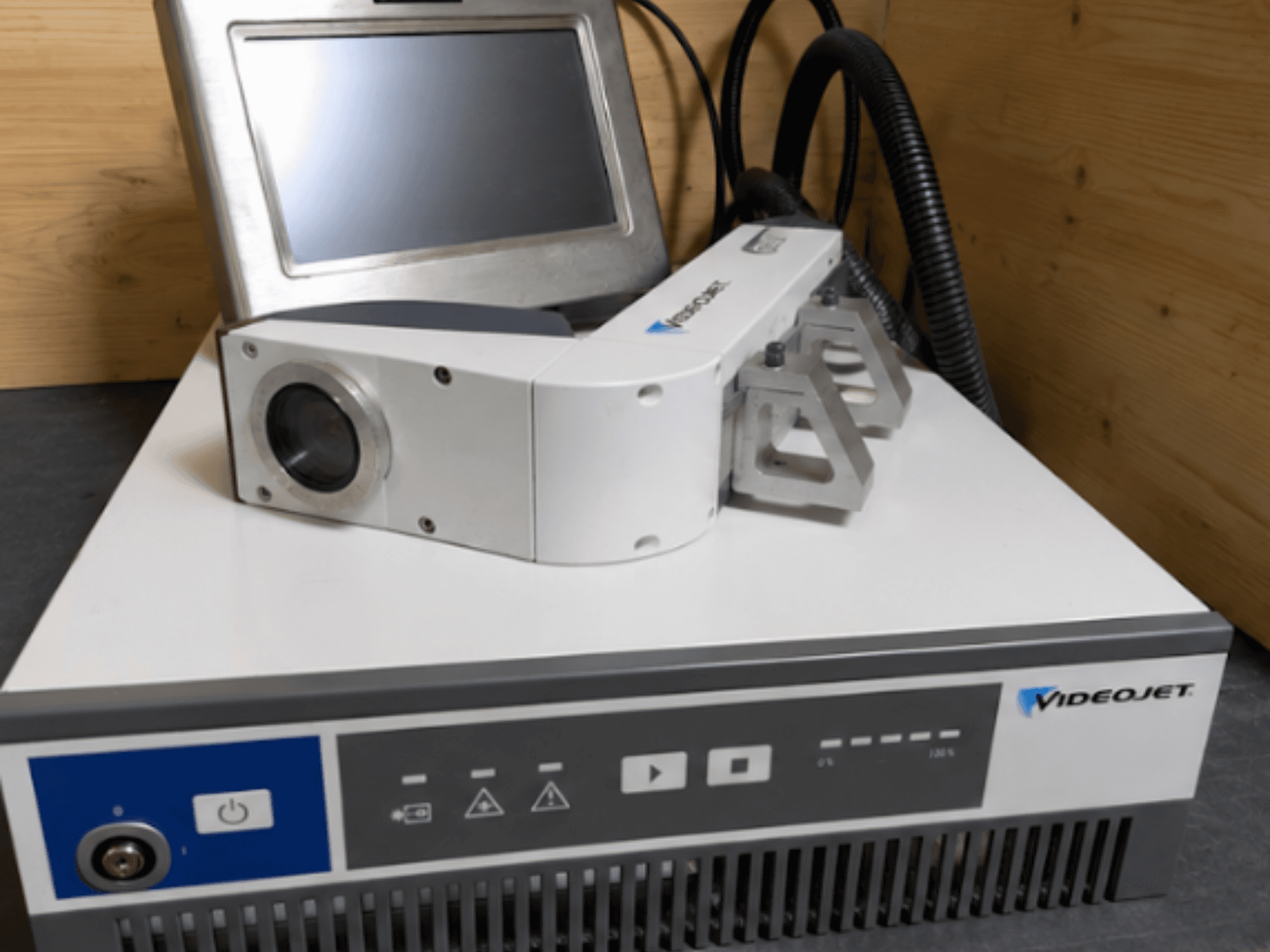 Máquina de gravação a laser Videojet 7230, vista frontal, mostrando o painel de controlo e a cabeça do laser com lente e acessório.
