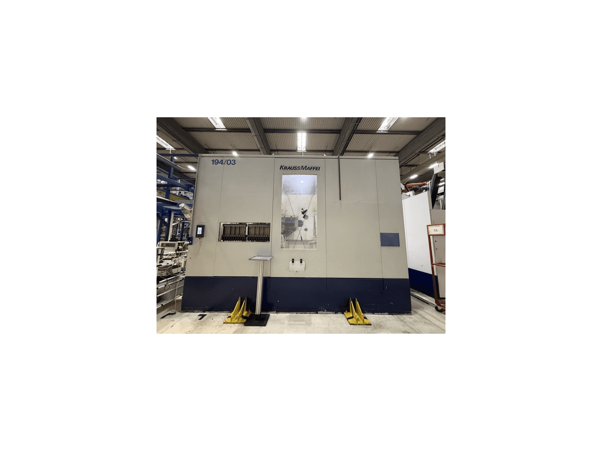 Máquina de moldagem por injeção hidráulica Krauss Maffei 4000-24500 MC, vista frontal que mostra o painel de controlo e a área de operação.