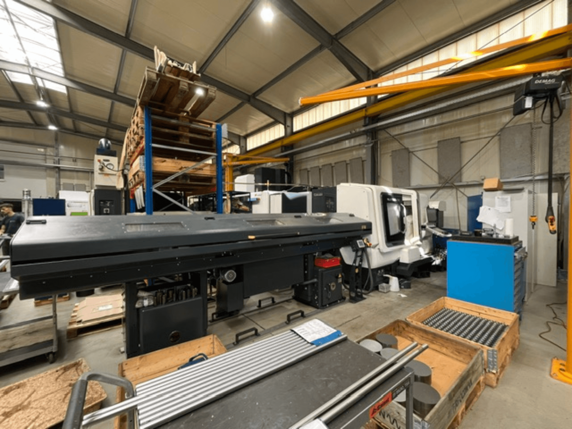 Torno horizontal DMG MORI MORI NLX 2500/700 SY num ambiente fabril, visto de lado, com as ferramentas e as paletes visíveis.
