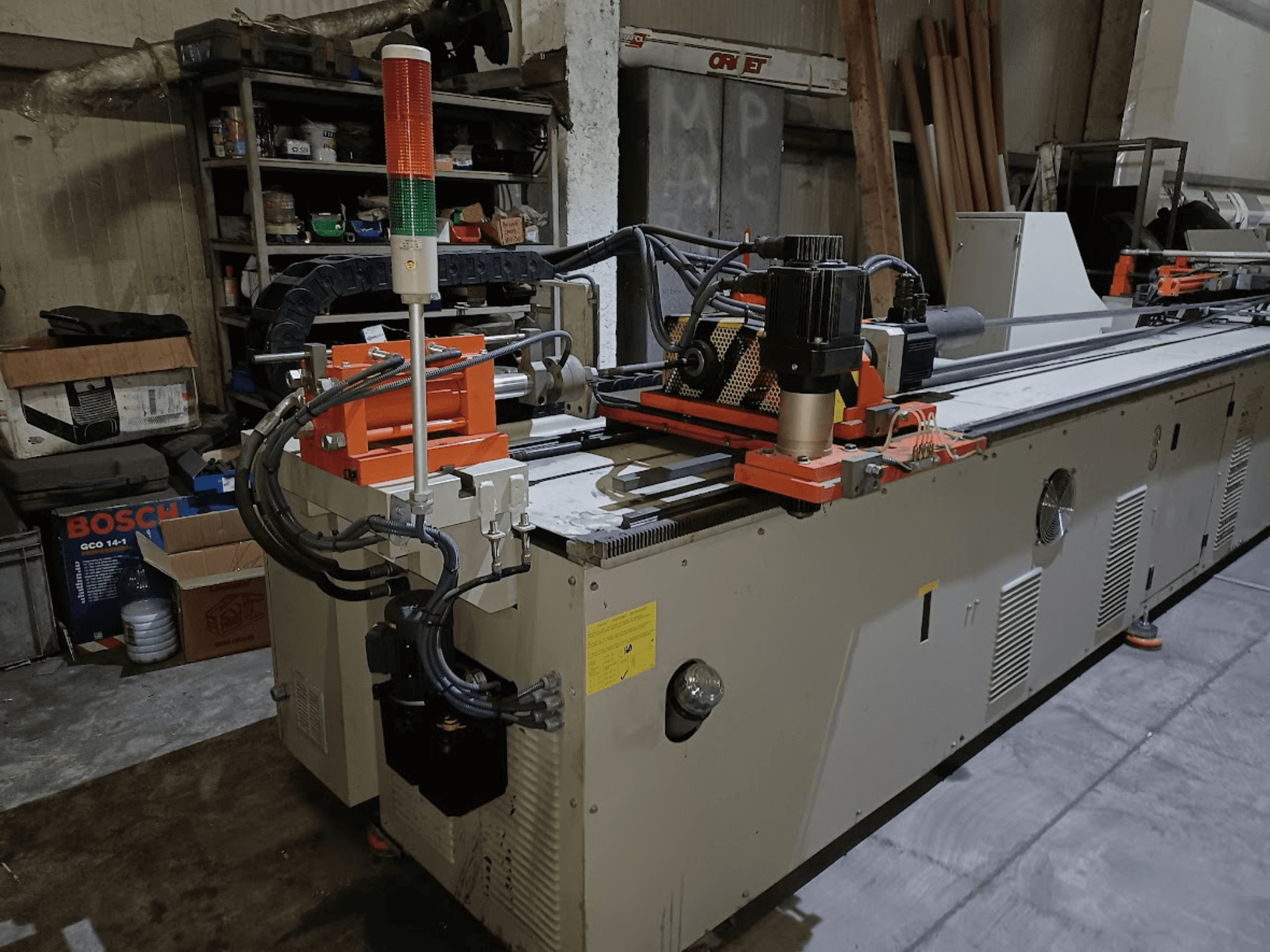 Máquina de dobragem CANSA CNC 51 R1, vista lateral, mostrando o painel de controlo, o motor e as luzes indicadoras num ambiente de oficina.