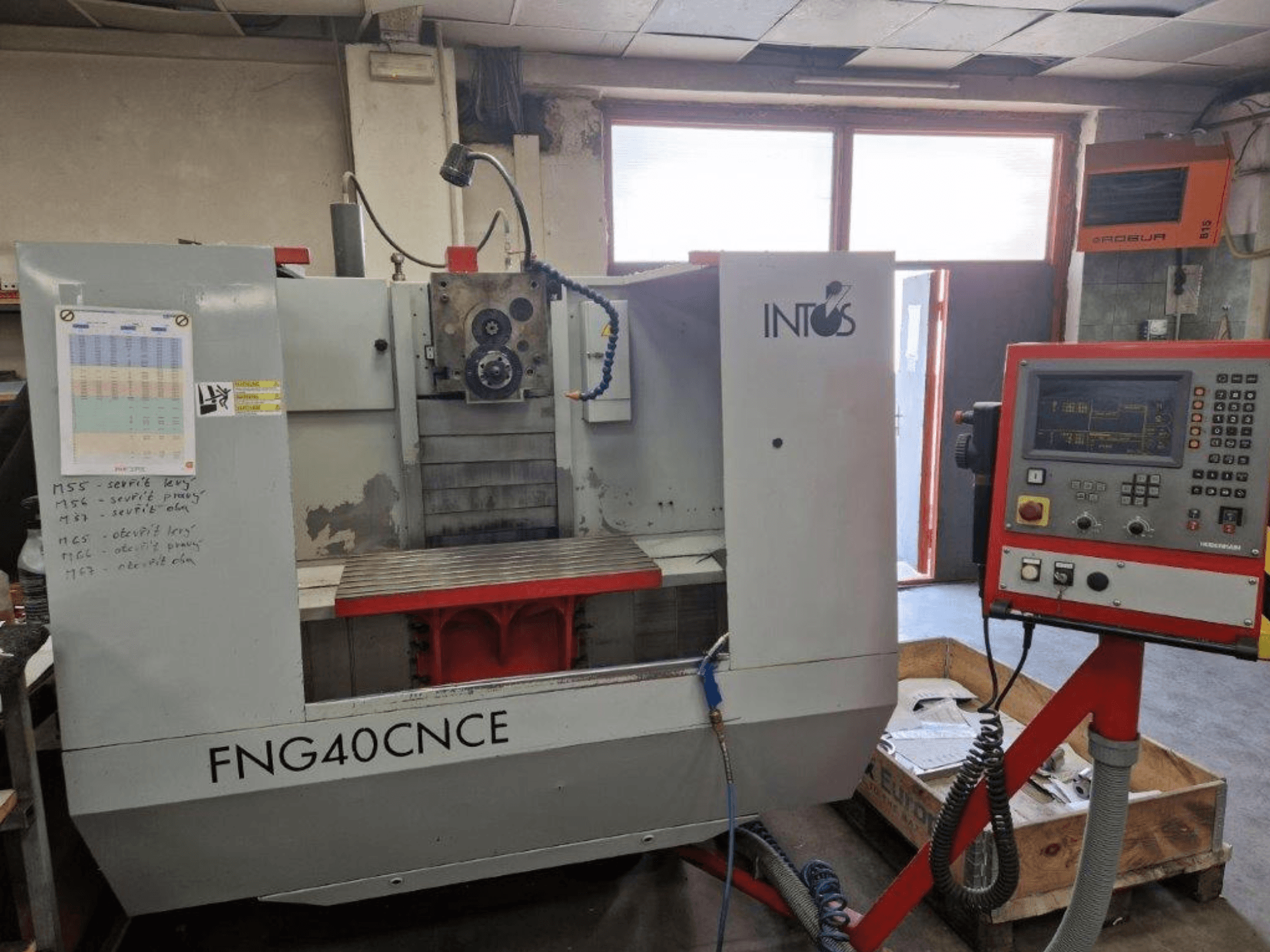 Máquina INTOS FNG40CNC, vista frontal, com painel de controlo, peças operacionais e uma mesa de trabalho em metal. Ideal para maquinação.
