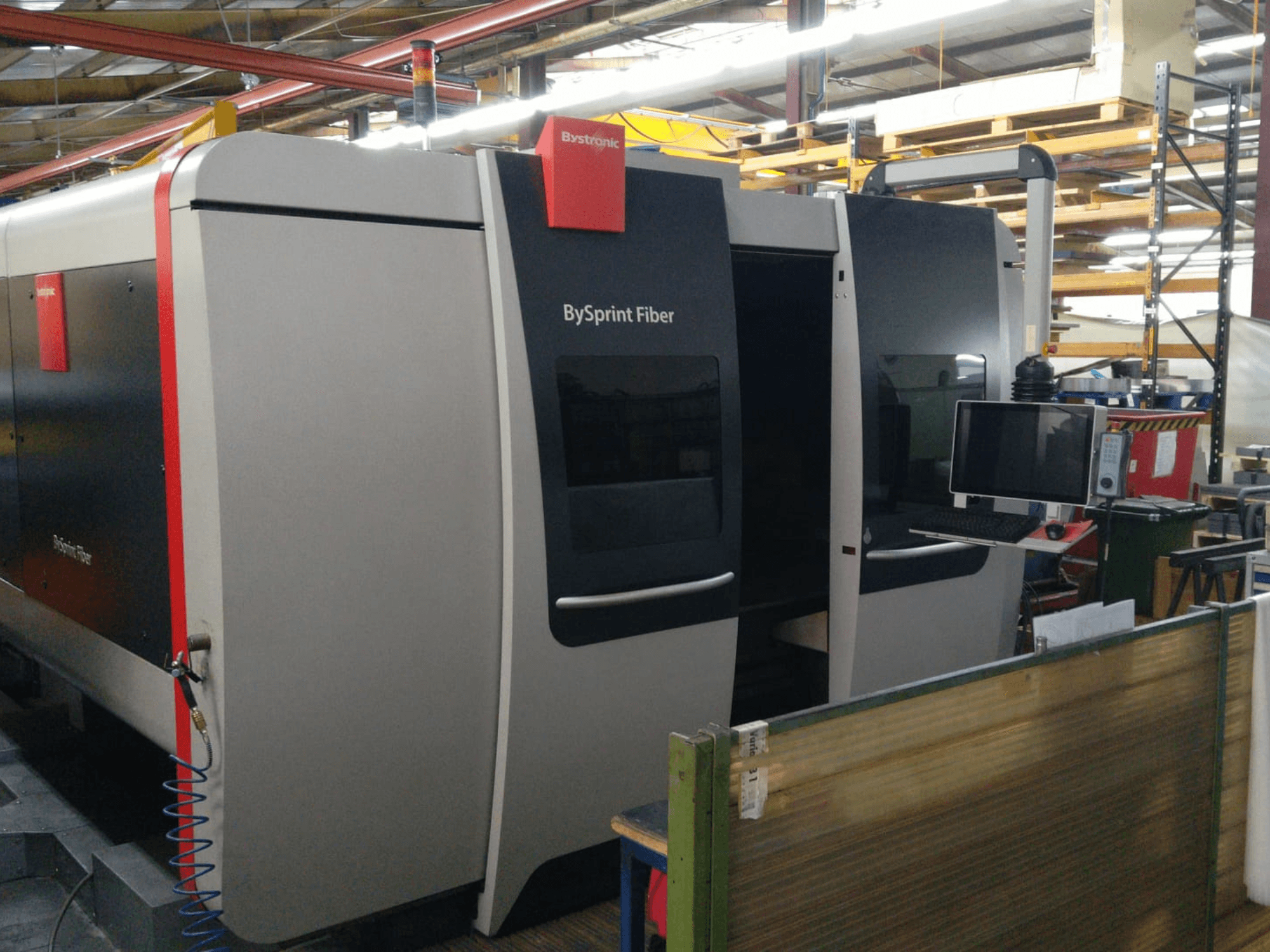 Cortador a laser de fibra Bystronic BySprint, vista frontal com painel de controlo, detalhes visíveis incluem duas portas e um monitor na lateral.