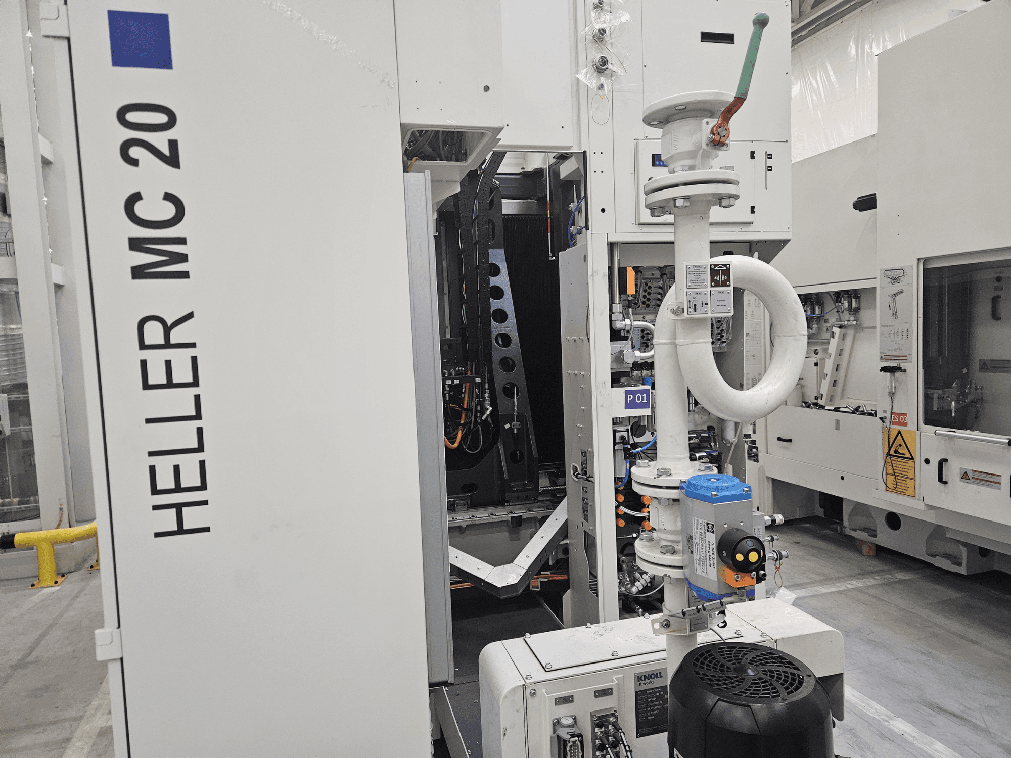 Máquina Heller MC 20 em ambiente de fábrica, mostrando o painel de controlo e os componentes mecânicos a partir de uma vista lateral.