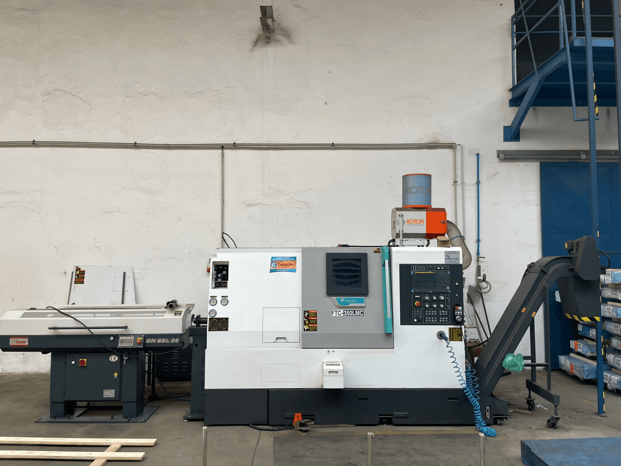 O torno horizontal FTC 350 LMC da Feeler numa oficina, mostrando o painel de controlo e as linhas de alimentação da ferramenta. Vista lateral.