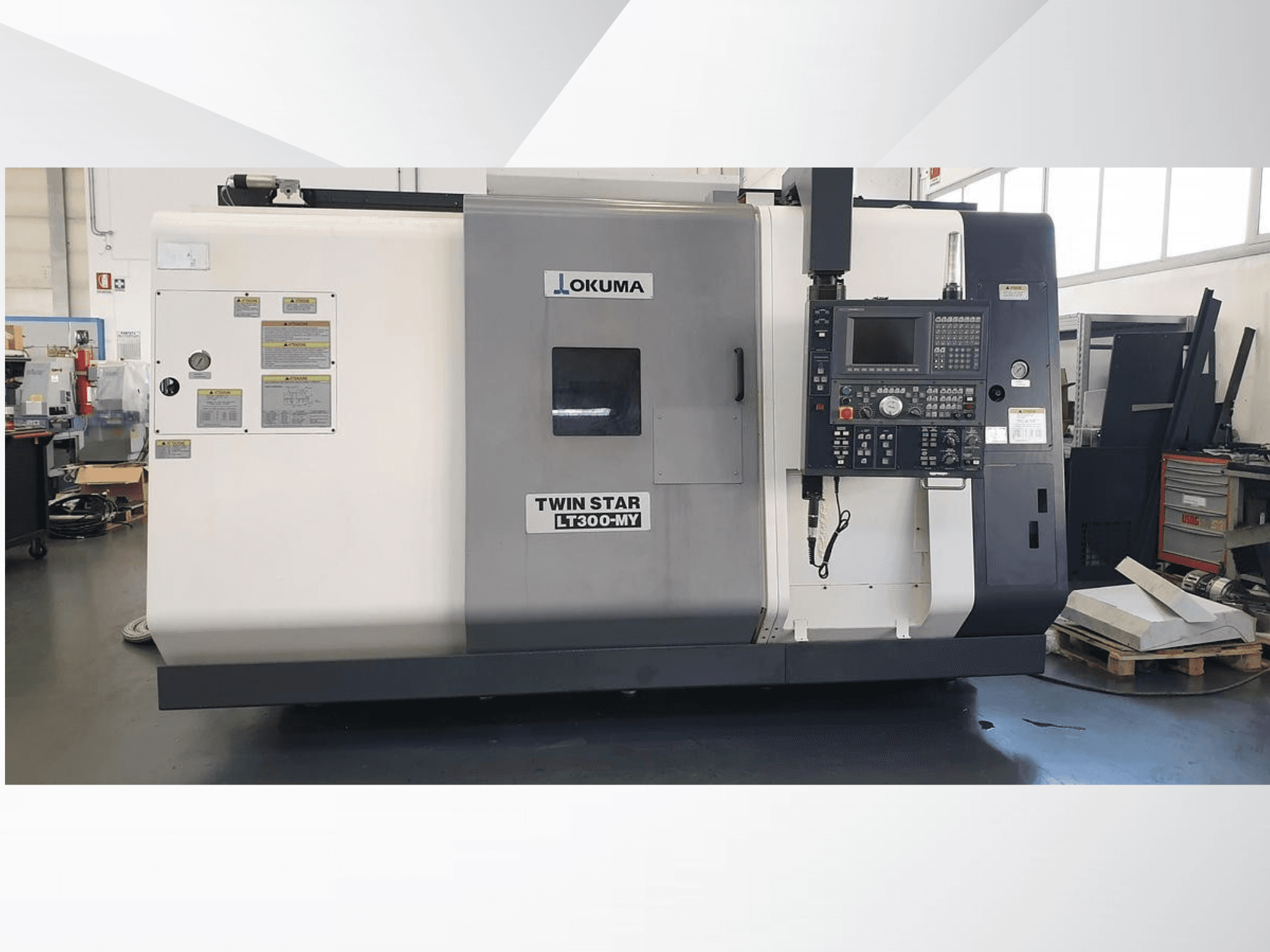 Torno CNC Okuma Twin Star LT300-MY, vista frontal com painel de controlo e etiquetas operacionais visíveis.