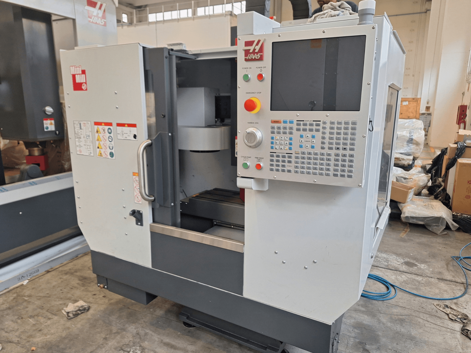 Centro de maquinagem vertical HAAS Mini Mill, visto de frente, com um painel de controlo com botões e um ecrã.