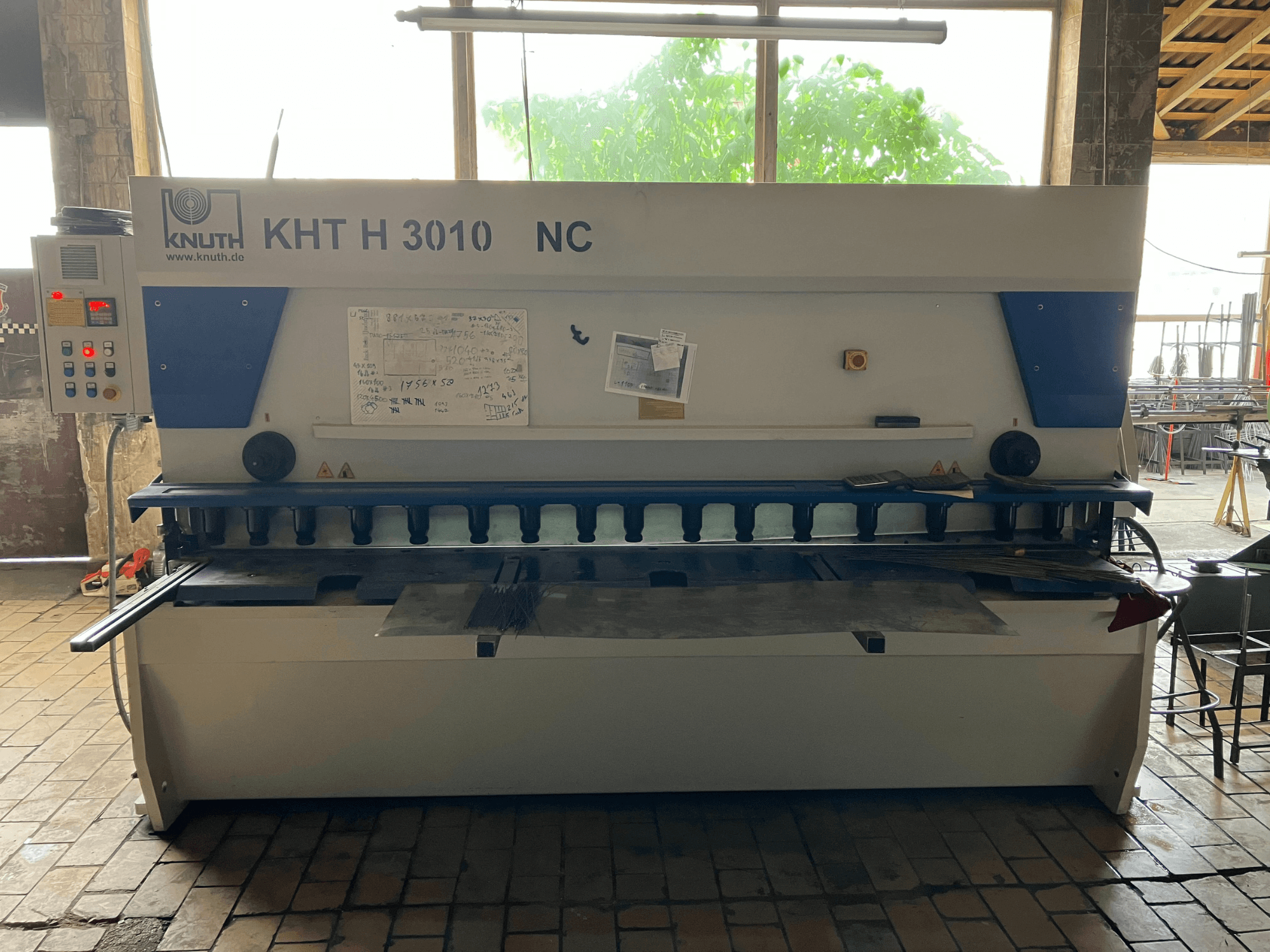 Máquina de corte hidráulica KNUTH KHT H 3010 NC vista de frente, com um painel de controlo e uma área de corte de metal.