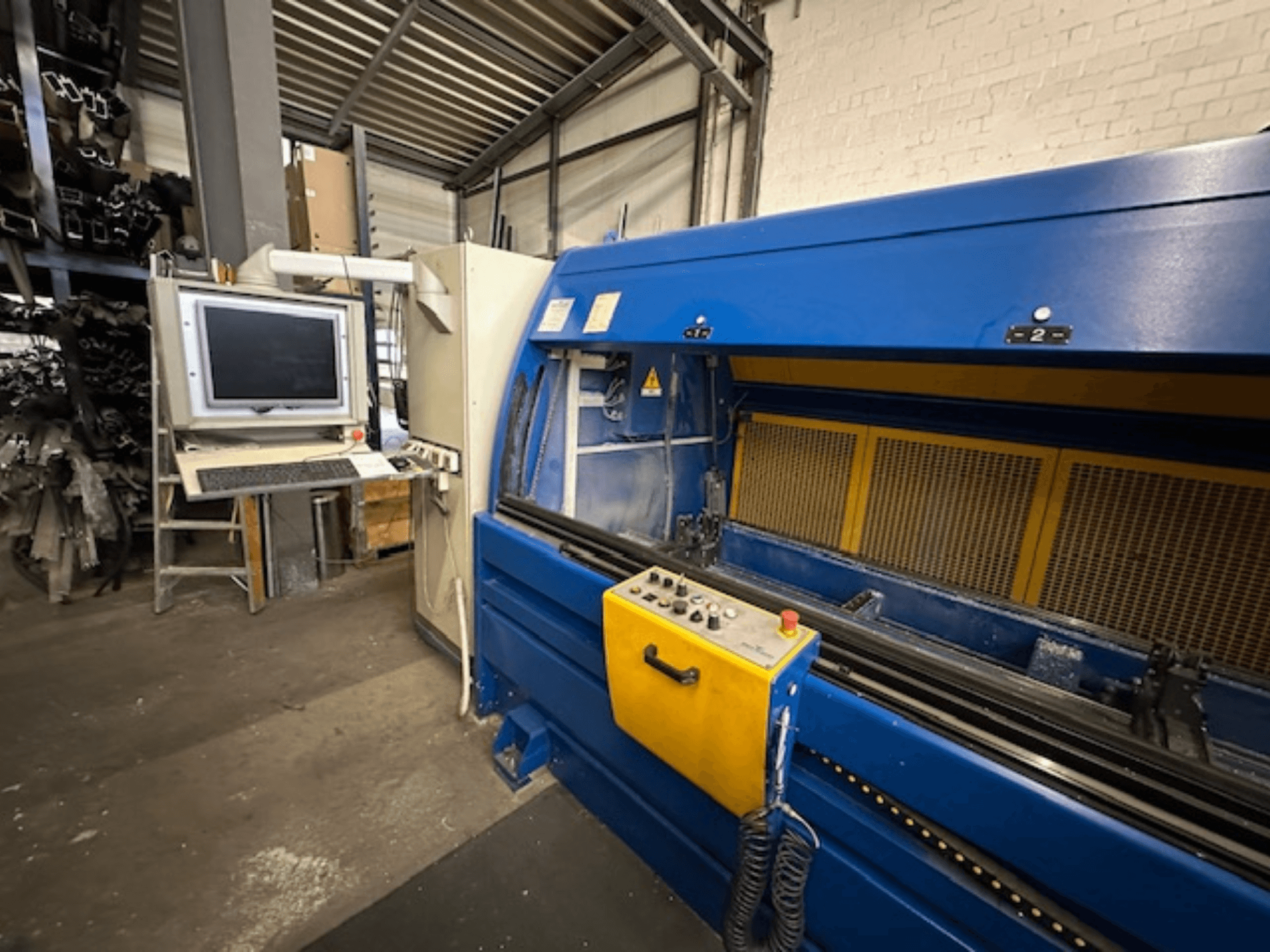 Vista frontal do SCHÜCO Profilbearbeitungscenter 299 650, um centro de maquinação universal com controlos e estação de trabalho computorizada.