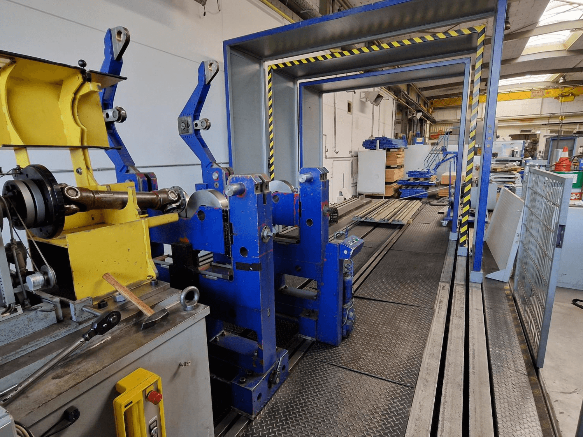 Máquina-ferramenta SCHENCK HM 70U BU, vista lateral que mostra a estrutura azul com componentes amarelos e o painel de controlo num ambiente industrial.