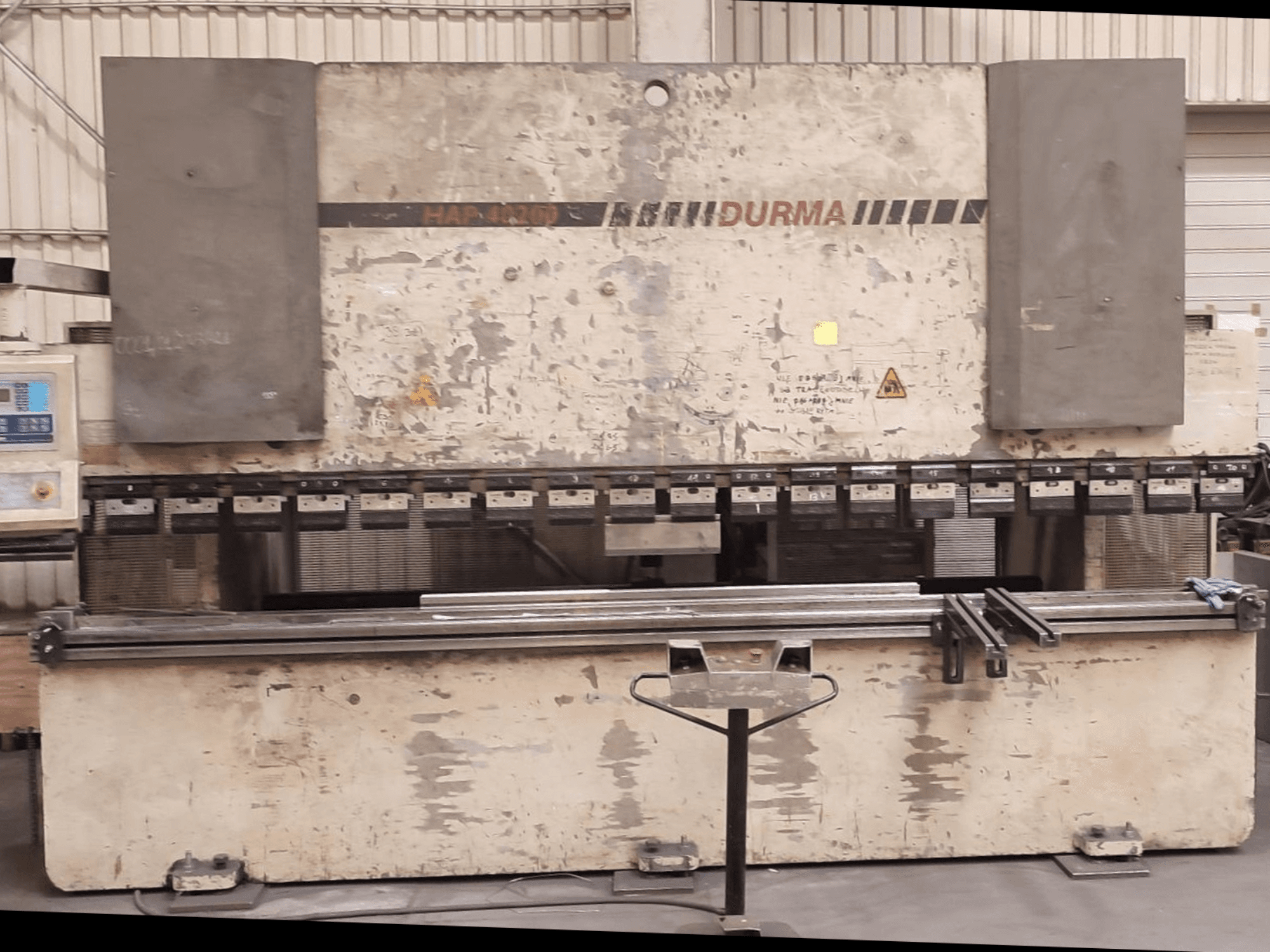 Vista frontal da prensa dobradeira Durma HAP 40200, com um exterior desgastado, painel de controlo e ferramentas de fixação visíveis na superfície de trabalho.