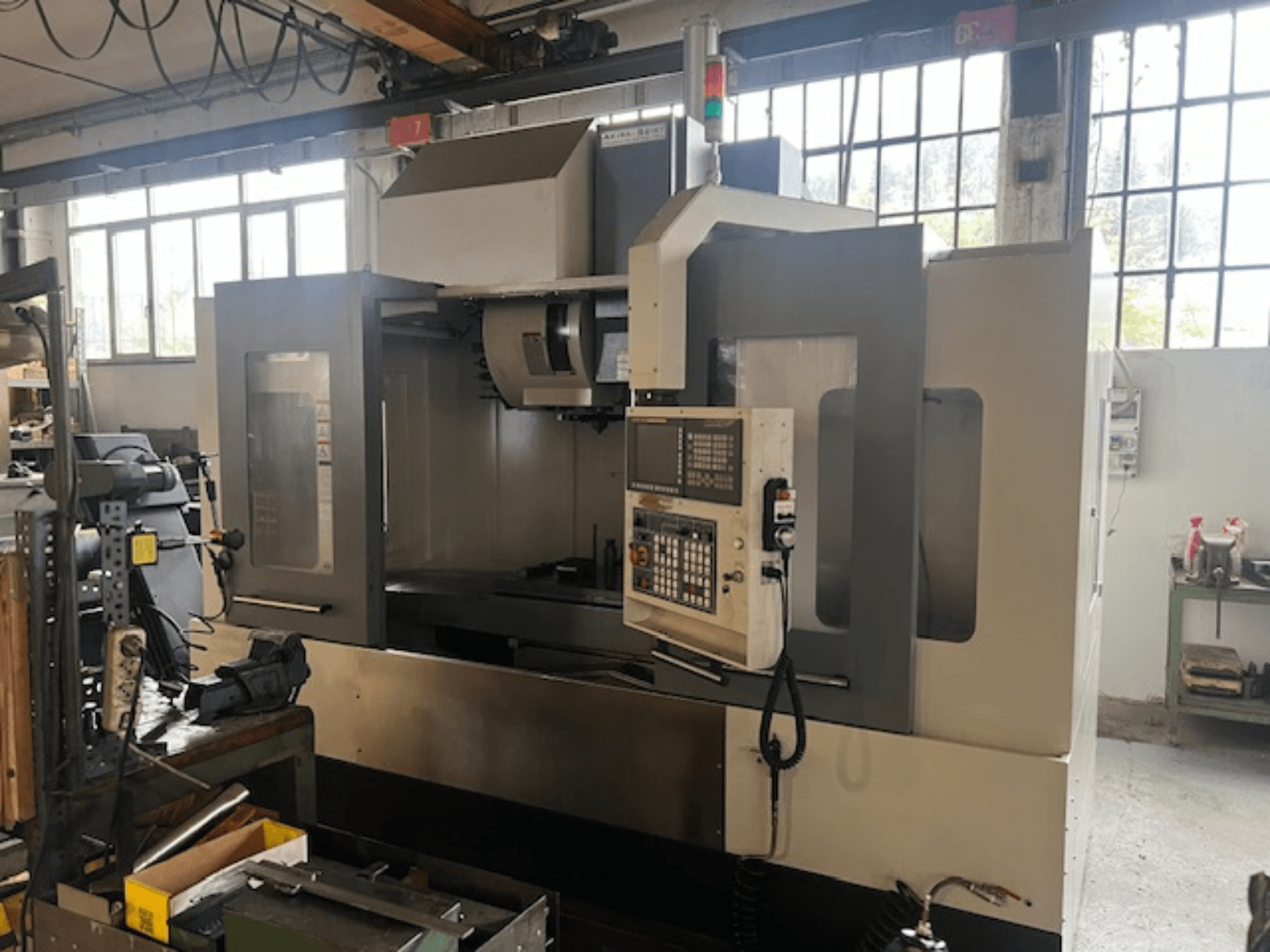 Fresadora CNC de alta tecnologia, vista frontal, com controlos digitais, indicadores de segurança básicos e um design compacto.