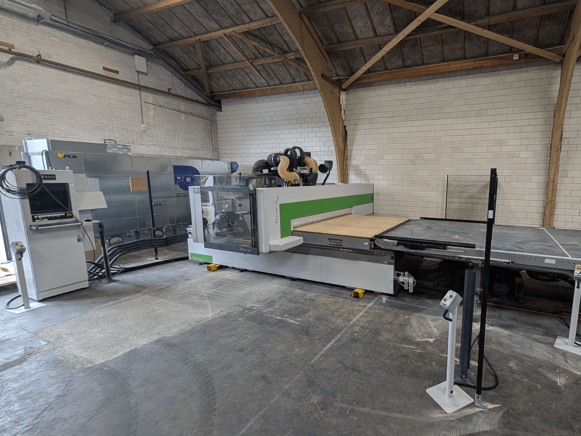 O centro de maquinação CNC PCK, vista frontal, possui uma grande base de corte, painel de controlo, sistema de extração de poeiras e design robusto.