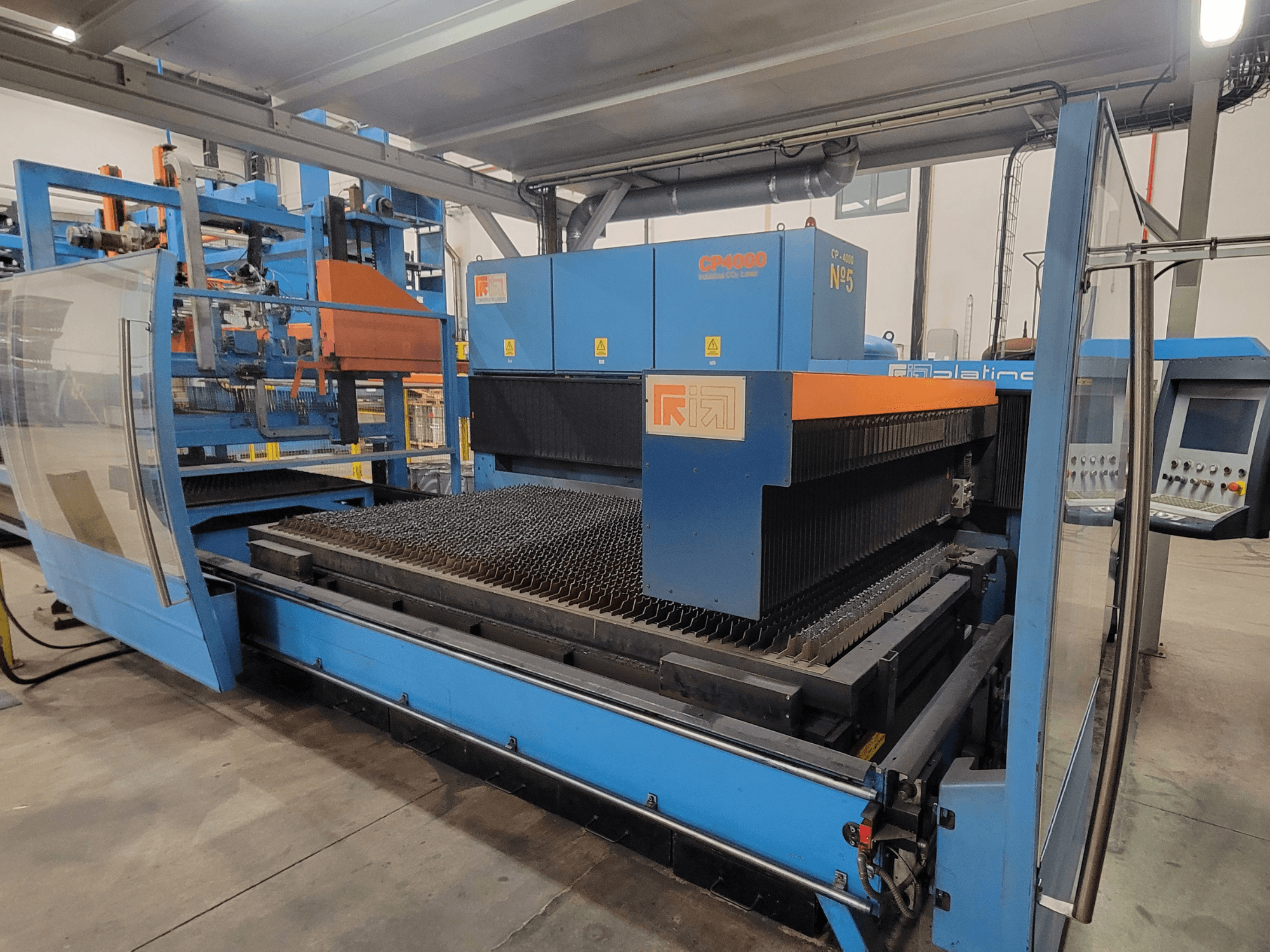 Máquina de corte a laser RIK CP4060 em azul, vista lateral mostrando a grelha de corte de metal e o painel de controlo. Ideal para aplicações industriais.