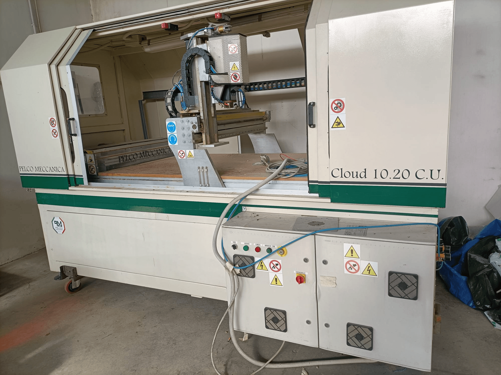 Tupia CNC MECCANICA CLOUD 10.20 C.U., vista frontal mostrando o painel de controlo e o espaço de trabalho, com etiquetas de segurança e mangueiras visíveis.