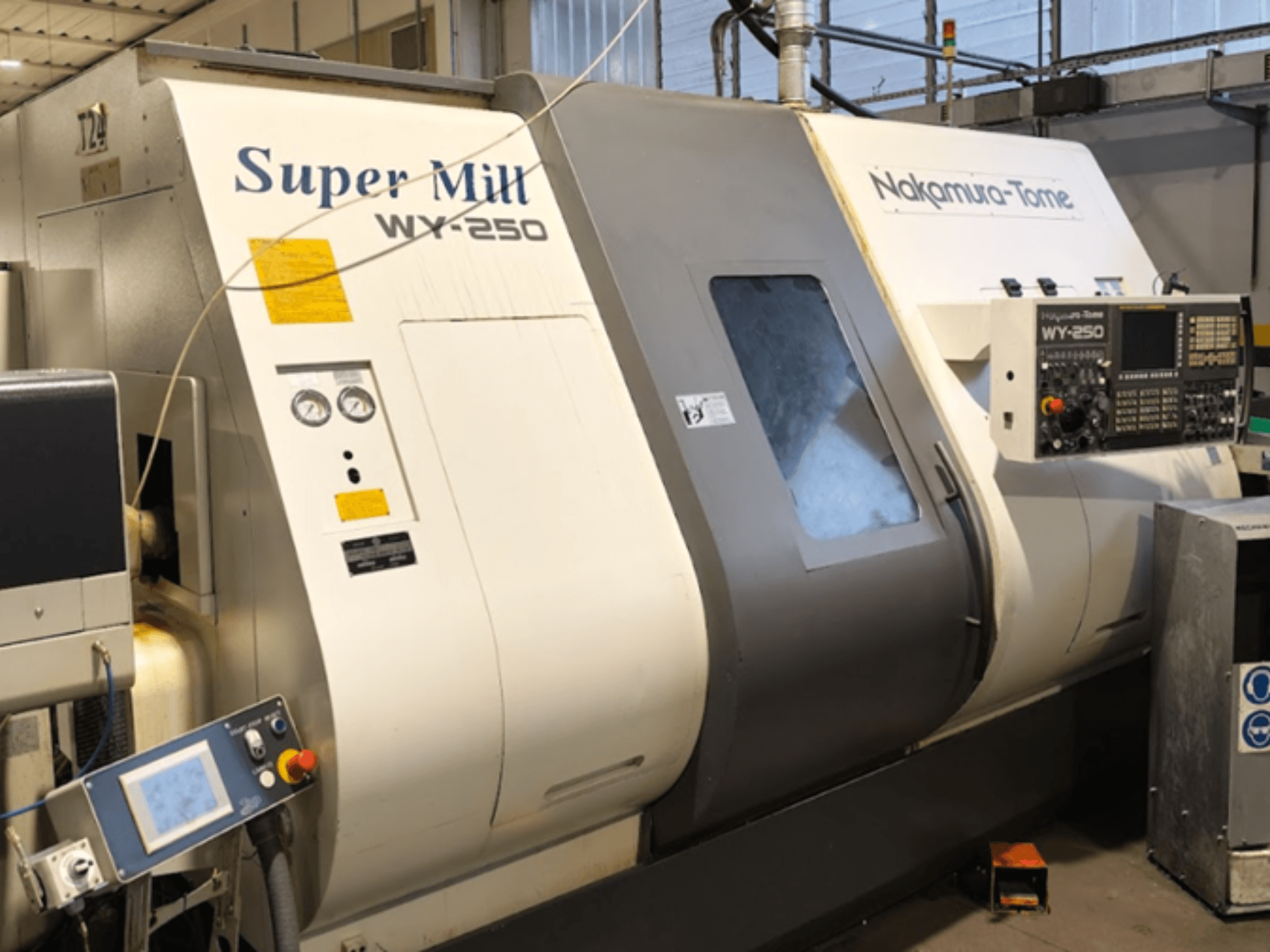 Máquina de torneamento horizontal NAKAMURA-TOME WY 250 em vista frontal; possui painel de controlo e visor, com a indicação "Super Mill".