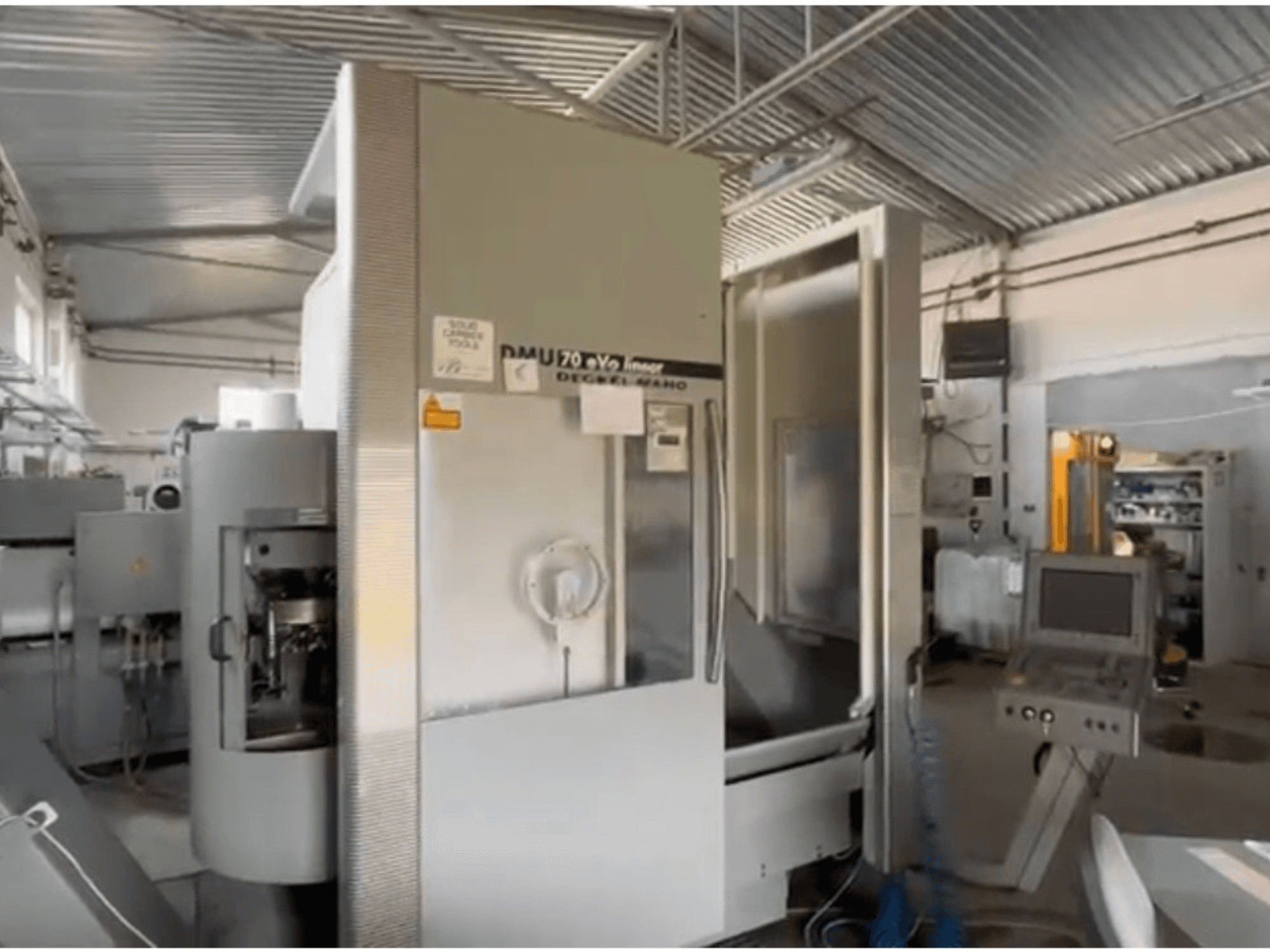 Máquina CNC linear DMU 70 eVo numa oficina, vista frontal, com um painel de controlo e um design moderno.