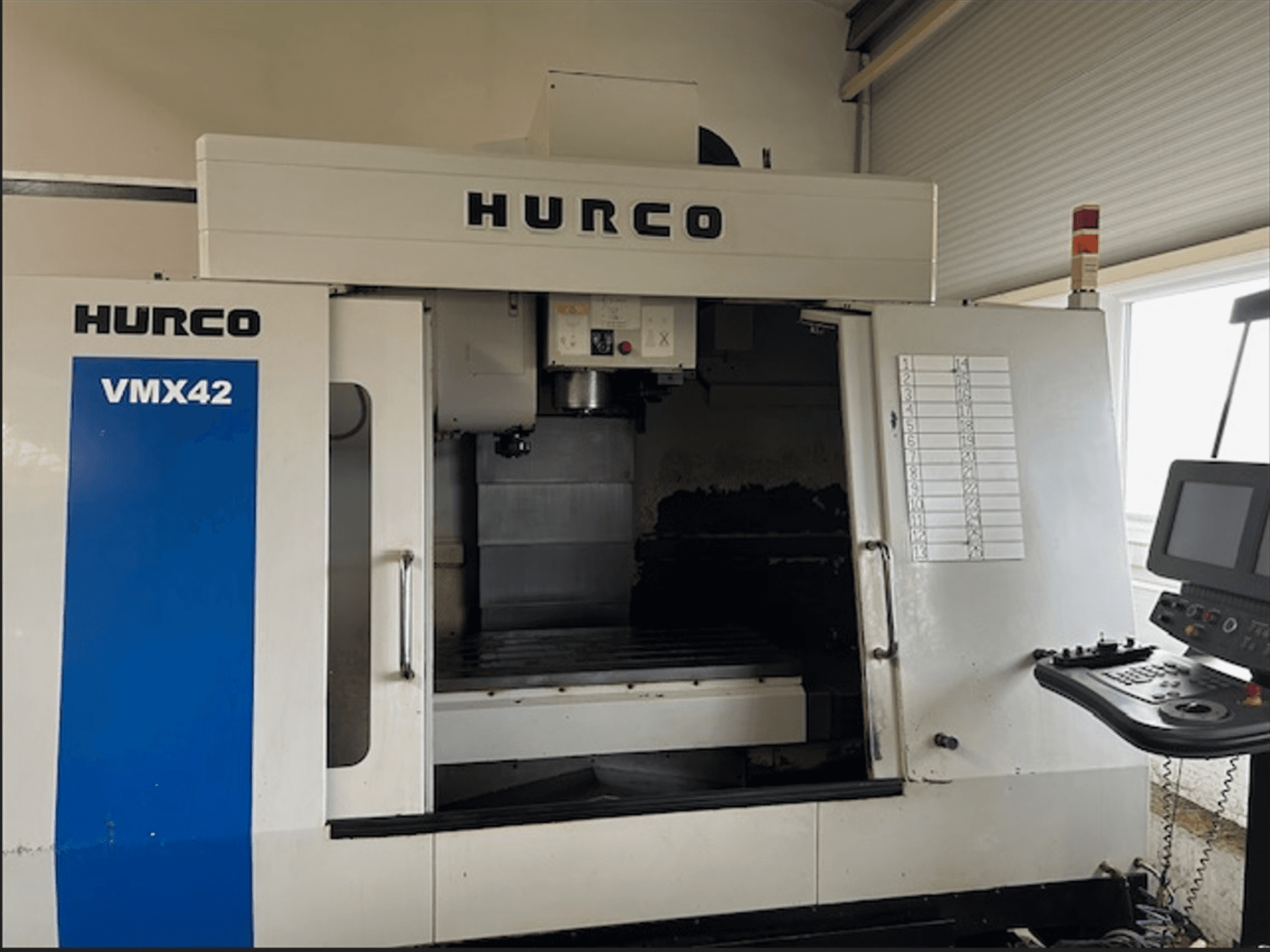 Fresadora CNC Hurco VMX42, vista frontal, com painel de controlo e espaço de trabalho aberto para operações de maquinagem.