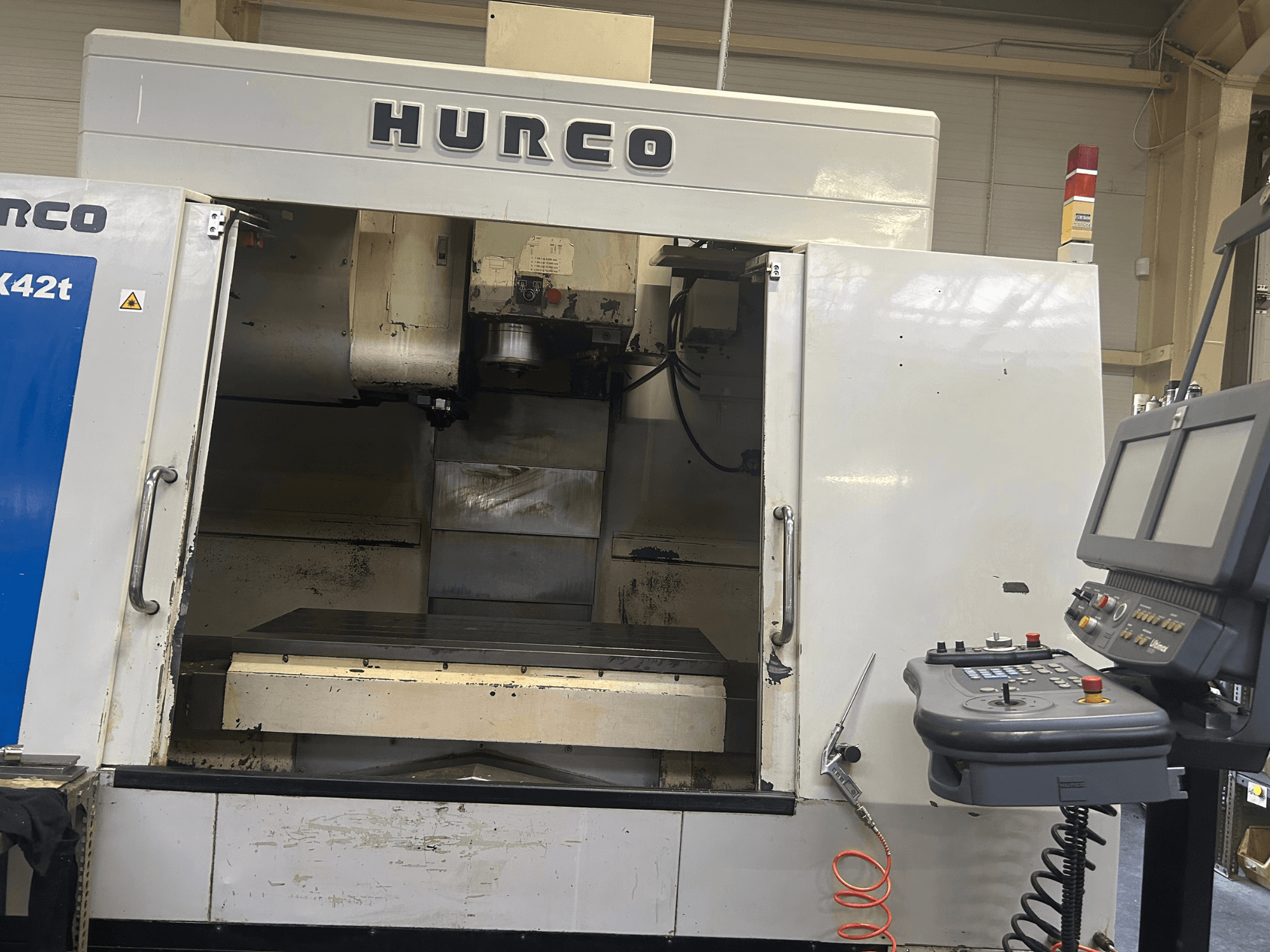 Fresadora CNC Hurco VMX42T em vista frontal, com um espaço de trabalho aberto e painel de controlo com botões e visor.