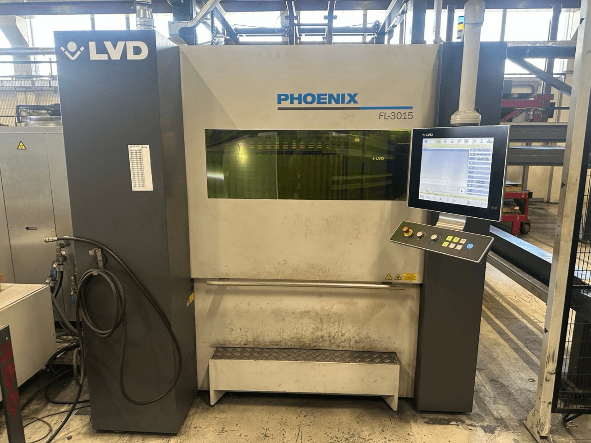 Máquina de corte a laser LVD Phoenix FL-3015, vista frontal, com um painel de controlo digital e tubos visíveis.