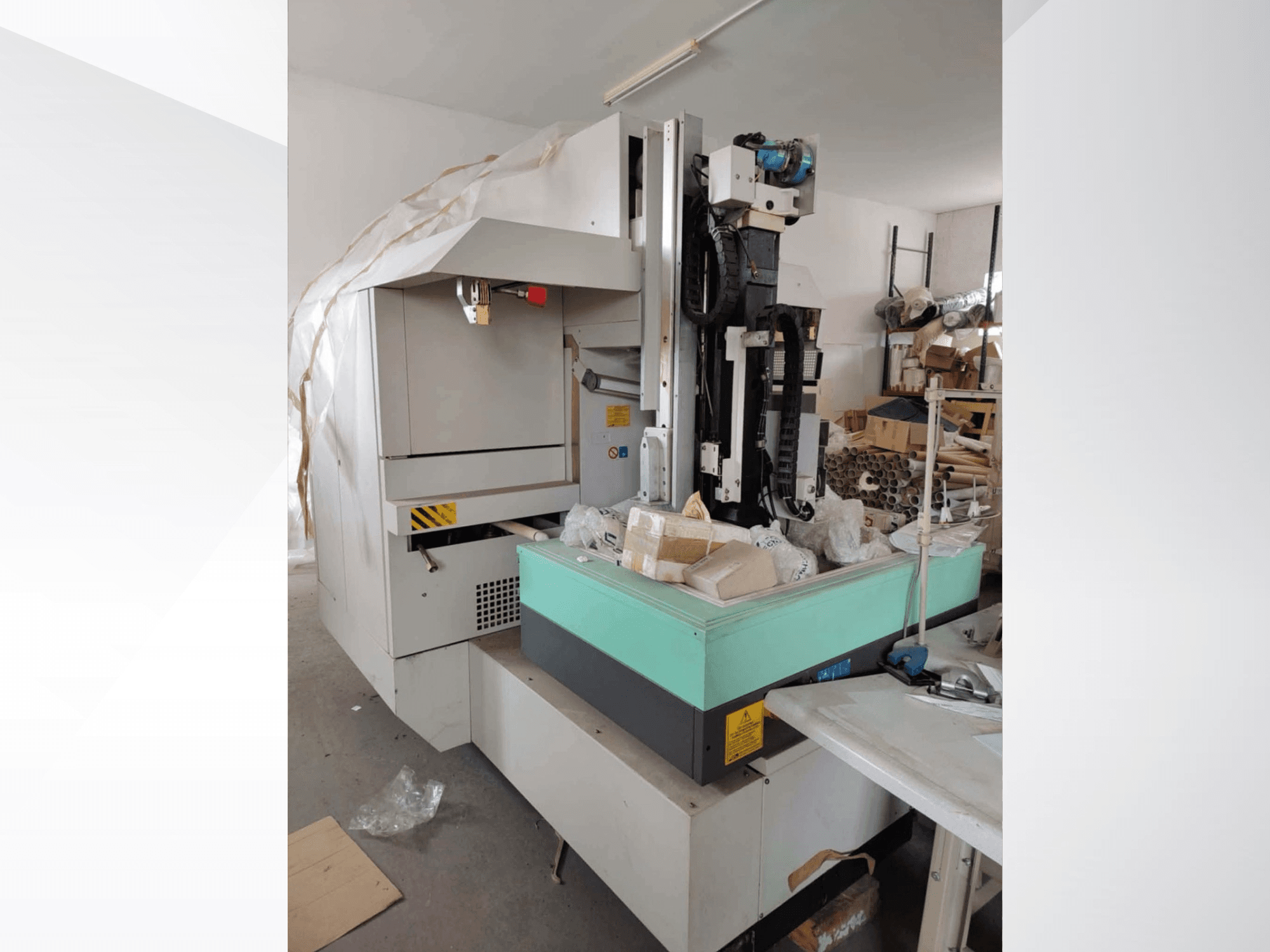 Máquina de electroerosão por penetração AGIE AGIETRON INTEGRAL 2 em vista lateral, com uma mesa de trabalho verde e várias ferramentas.