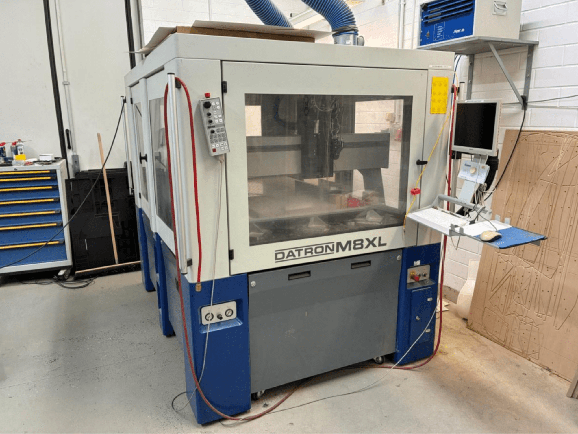 Máquina CNC DATRON M8XL numa oficina, vista frontal com painel de controlo e monitor montado ao lado.