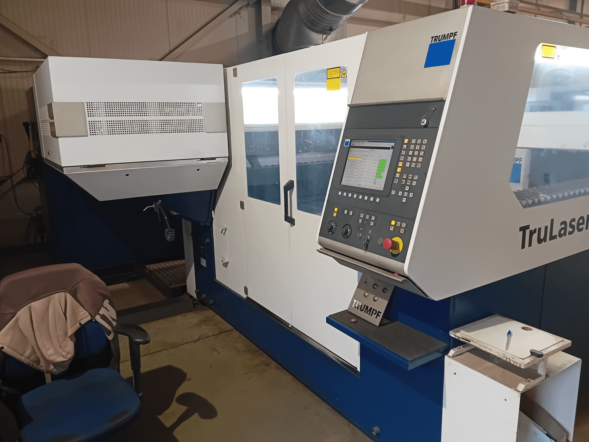 Máquina de corte a laser TRUMPF TruLaser 3030 CO2, vista frontal, mostrando o painel de controlo e a estação do operador.