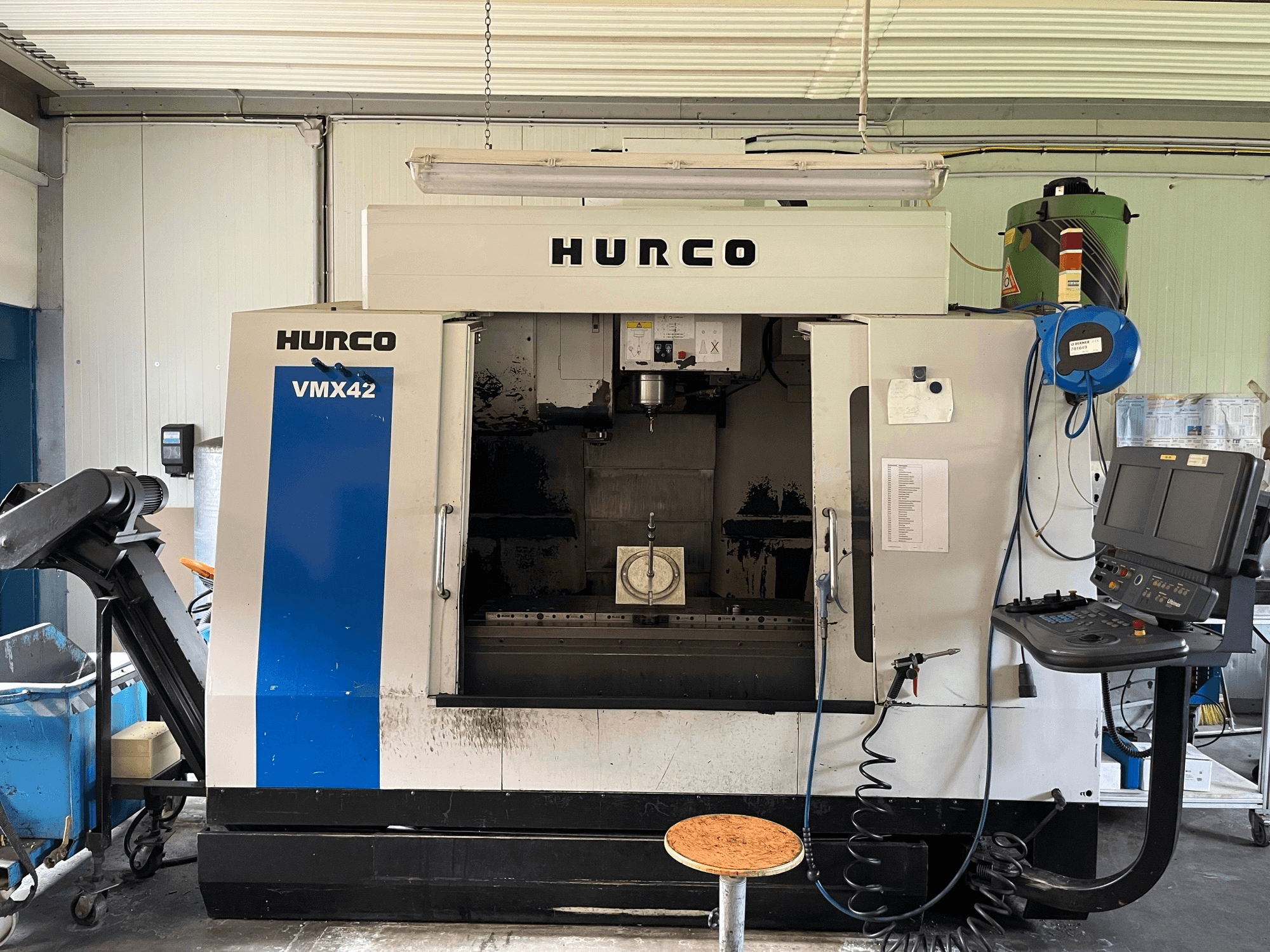 Centro de maquinação vertical Hurco VMX 42 em vista lateral, mostrando o painel de controlo, o fuso e a configuração da peça de trabalho.