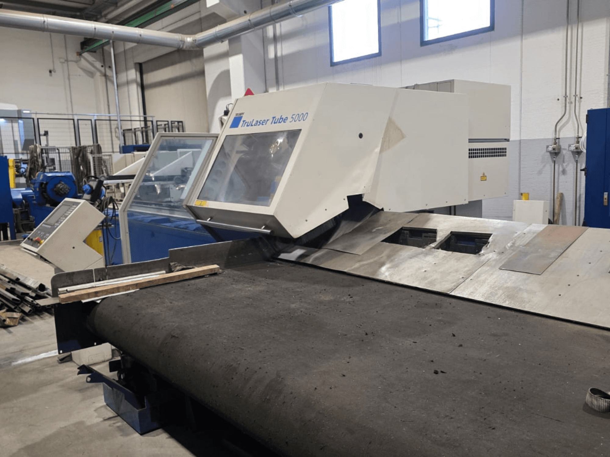 Máquina de corte de tubos TRUMPF LASERTUBE 5000, vista de frente, mostrando a área de corte e o painel de controlo.