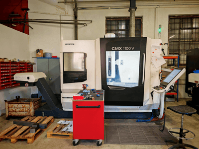 Centro de maquinagem vertical DMG MORI CMX 1100 V na oficina, vista frontal, mostrando o painel de controlo e as ferramentas à sua volta.