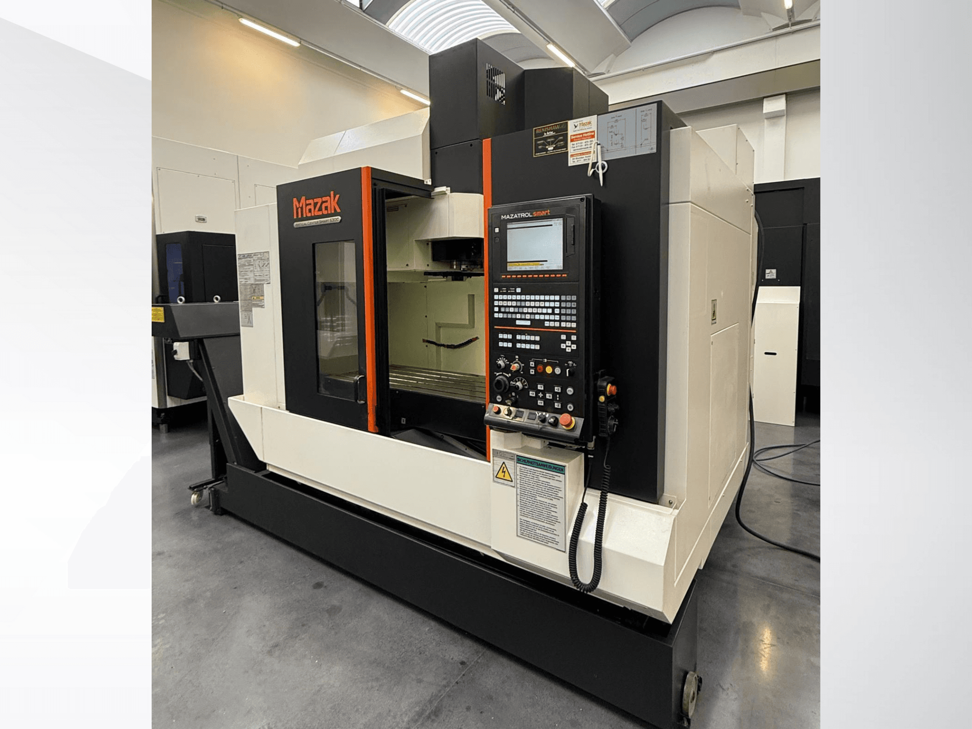 Máquina CNC Mazak, vista frontal, com um painel de controlo e uma área de trabalho espaçosa com ferramentas de corte de precisão.