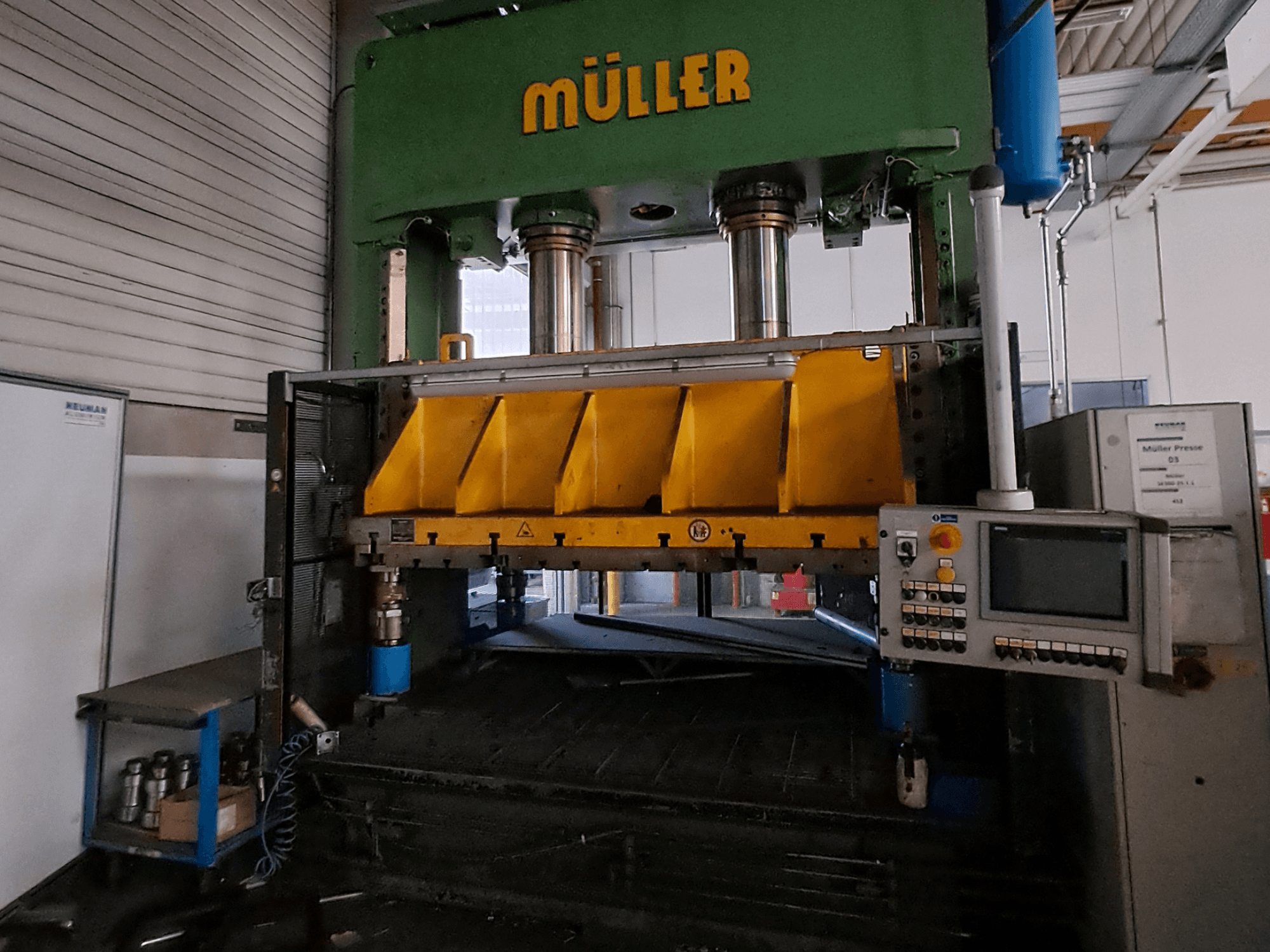 Vista frontal de uma prensa para metal Müller SE 300-25.1.1, com componentes de prensagem amarelos e um painel de controlo na lateral.