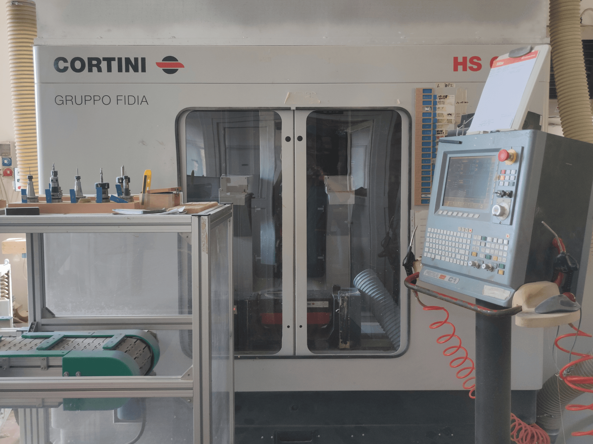Vista frontal do centro de maquinação vertical CORTINI HS 644, com painel de controlo, ferramentas em exposição e componentes da máquina visíveis.