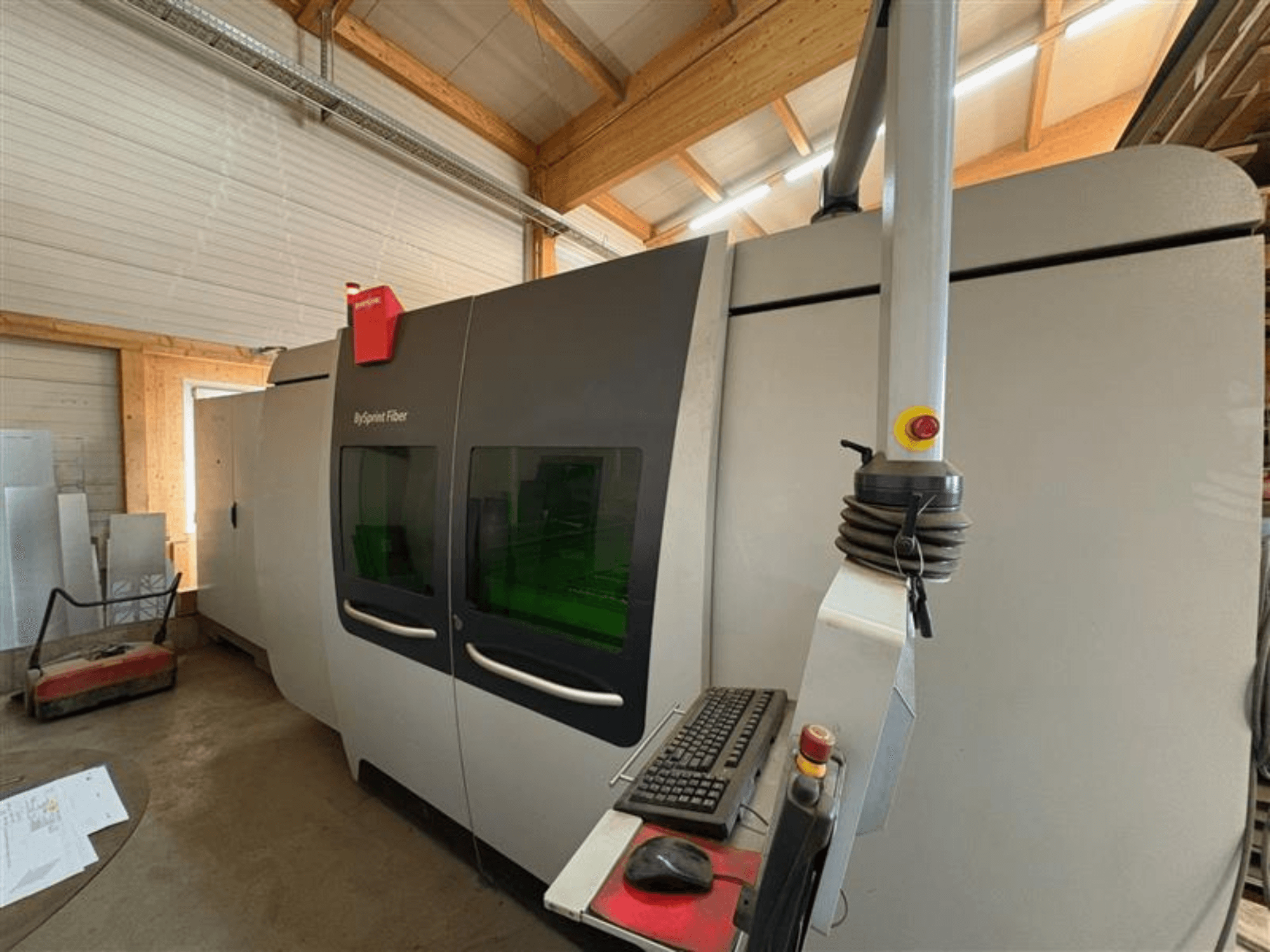 Máquina de corte ByJet Fiber da Bystronic numa oficina, vista frontal mostrando o painel de controlo e as duas janelas verdes de visualização.