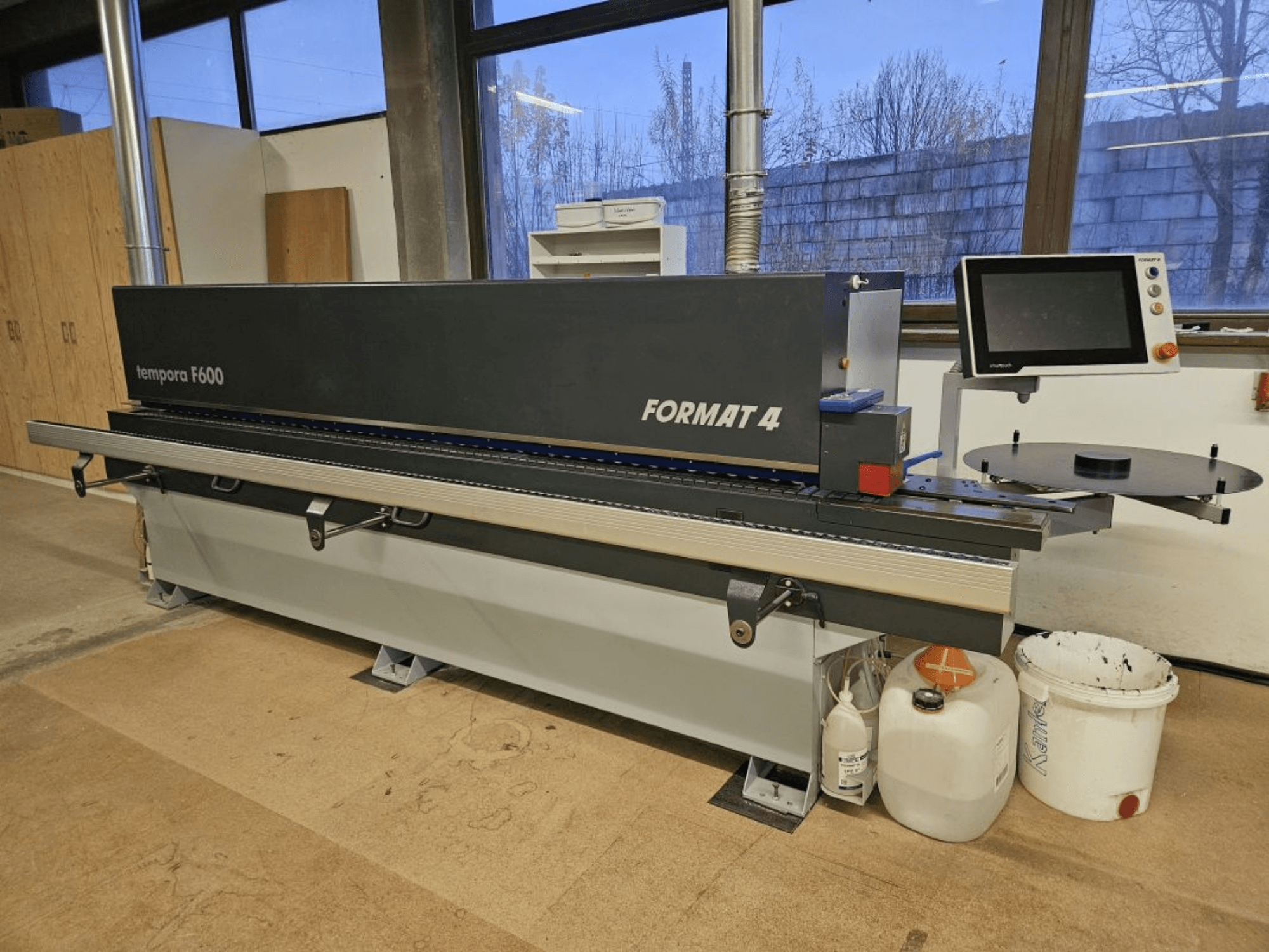 Templora F600 da Format 4, vista frontal de uma máquina para trabalhar madeira com ecrã digital, mesa de corte e recipientes de armazenamento.