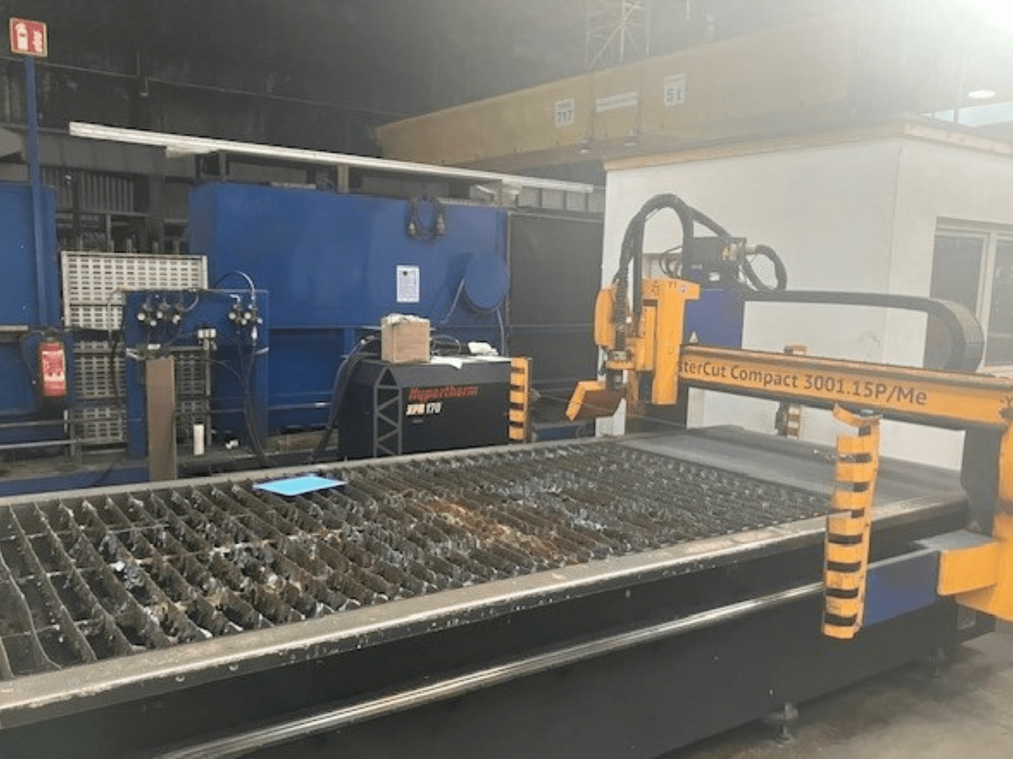 Máquina de corte por plasma Hypertherm MasterCut Compact 3001.15P/Me em vista lateral, mostrando a mesa de corte e o painel de controlo.