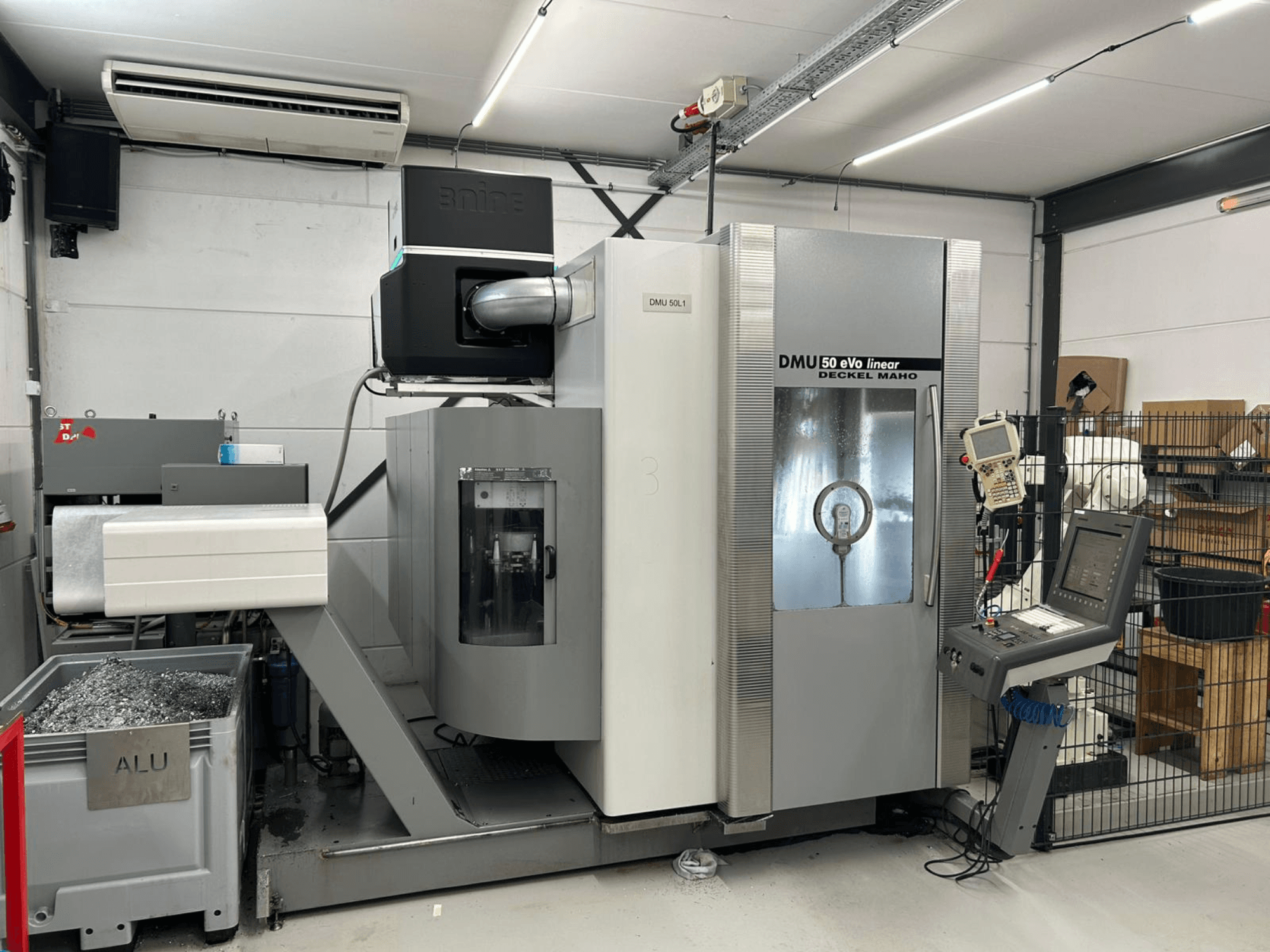 Fresadora linear DMU 50 eVo da Deckel Maho, vista frontal, com painel de controlo e recipiente para aparas.