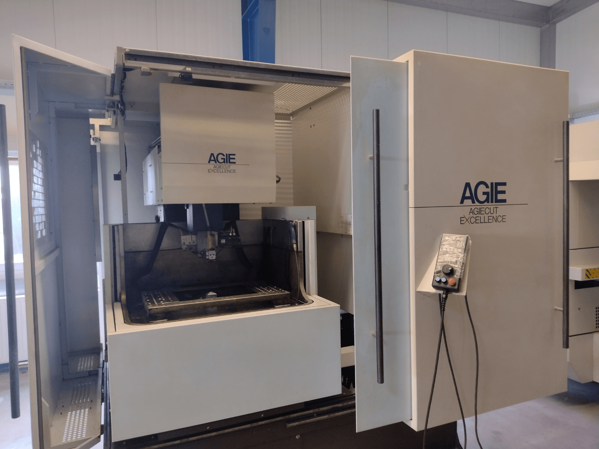 Máquina de eletroerosão por fio AGIE Progress 3, vista frontal, com armário aberto, painel de controlo e área de corte.