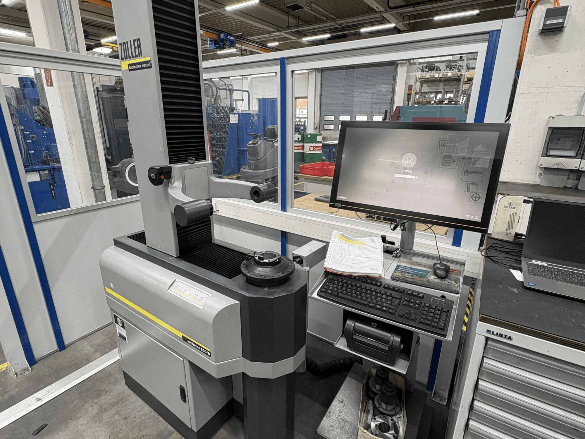 Máquina de medição ótica Zoller Venturion 600/8 numa oficina, com um monitor, teclado e plataforma de medição em vista lateral.