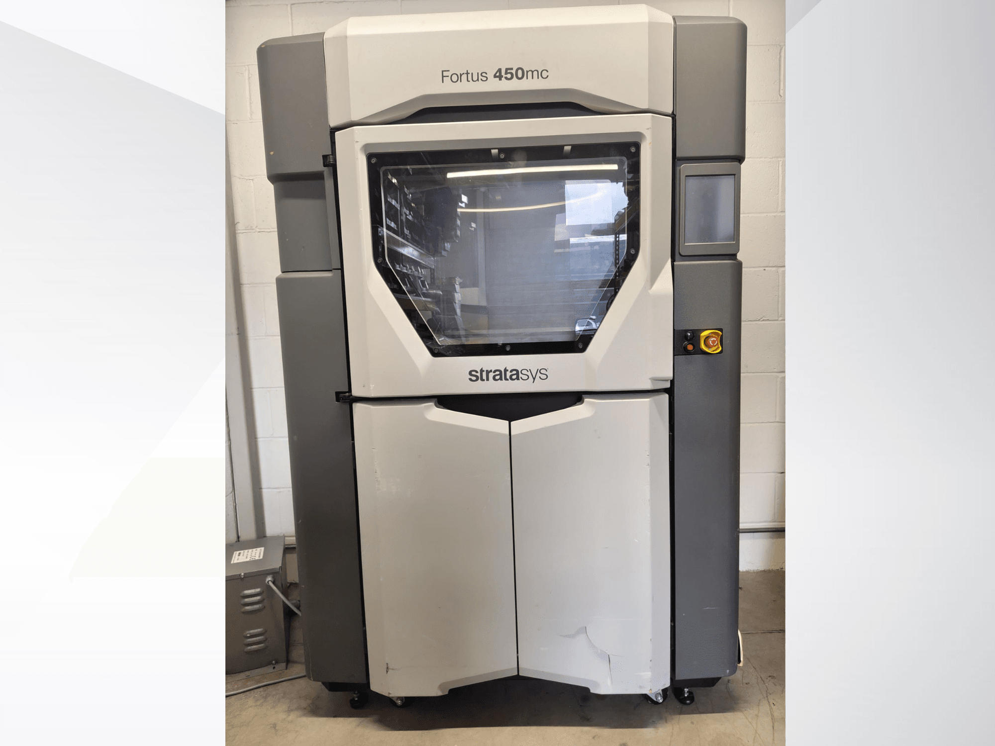 Máquina de processamento de plástico Stratasys Fortus 450mc, vista frontal, com uma grande janela, painel de controlo e design industrial.
