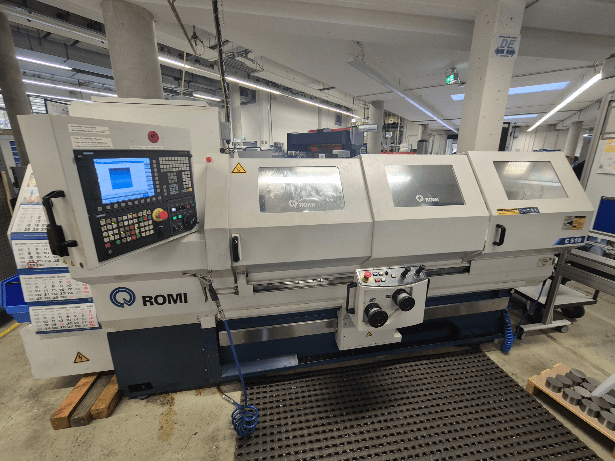 Torno Romi C510 visto de frente, com um painel de controlo digital e três tampas de proteção. Inclui etiquetas de segurança.