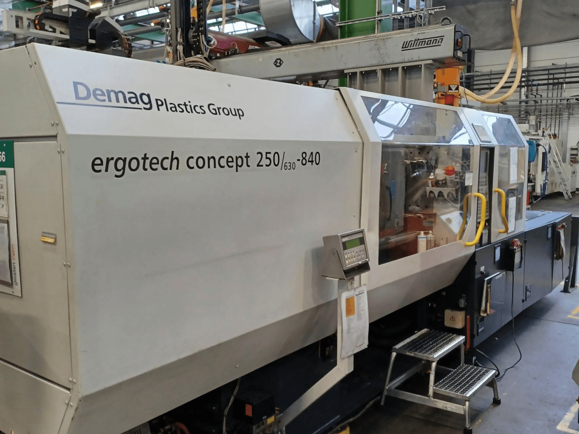 Máquina de moldagem por injeção Demag ergotech concept 250/630-840, vista frontal, mostrando os controlos digitais e as coberturas de segurança transparentes.