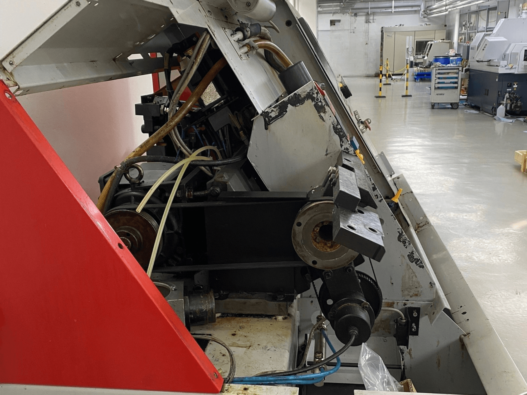 EMCO Emcoturn 325 máquina de tornear horizontal, vista lateral mostrando componentes de acionamento e hidráulicos em ambiente industrial.