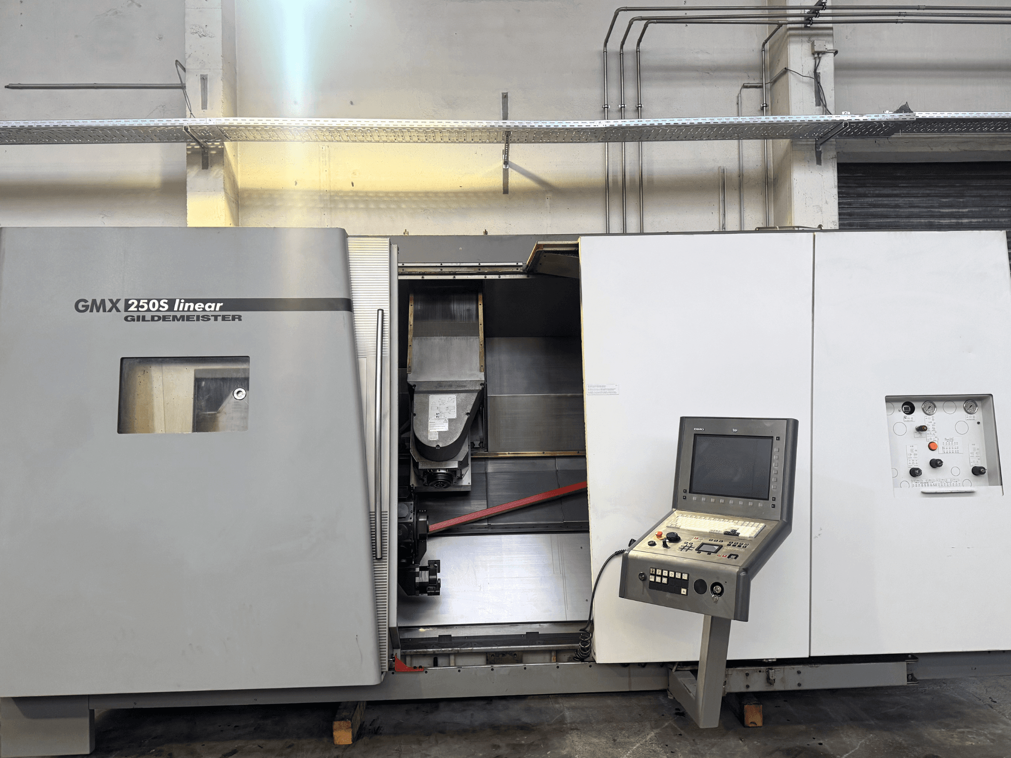 Máquina CNC linear Gildemeister GMX 250S, vista frontal, mostrando o painel de controlo e a área de trabalho aberta.
