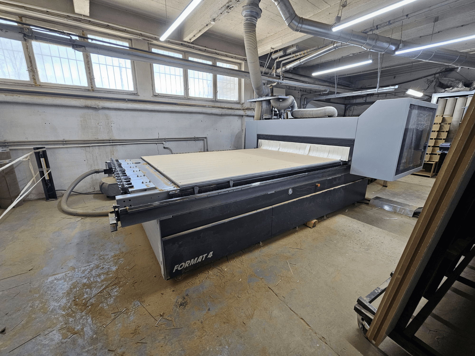 CNC Router FORMAT4 Profit H80 21.31, vista lateral mostrando a grande mesa de trabalho e o painel de controlo numa oficina.