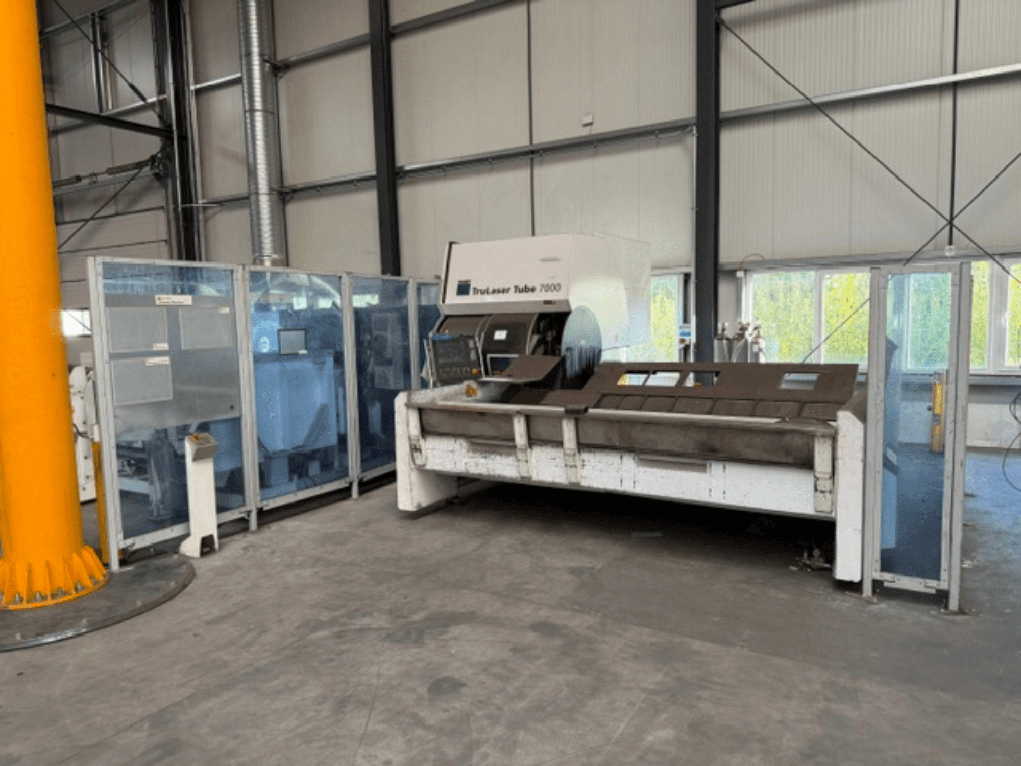 TruLaser Tube 7000 da TRUMPF, vista frontal de uma máquina de corte de tubos num ambiente industrial bem iluminado, com os comandos operacionais visíveis.