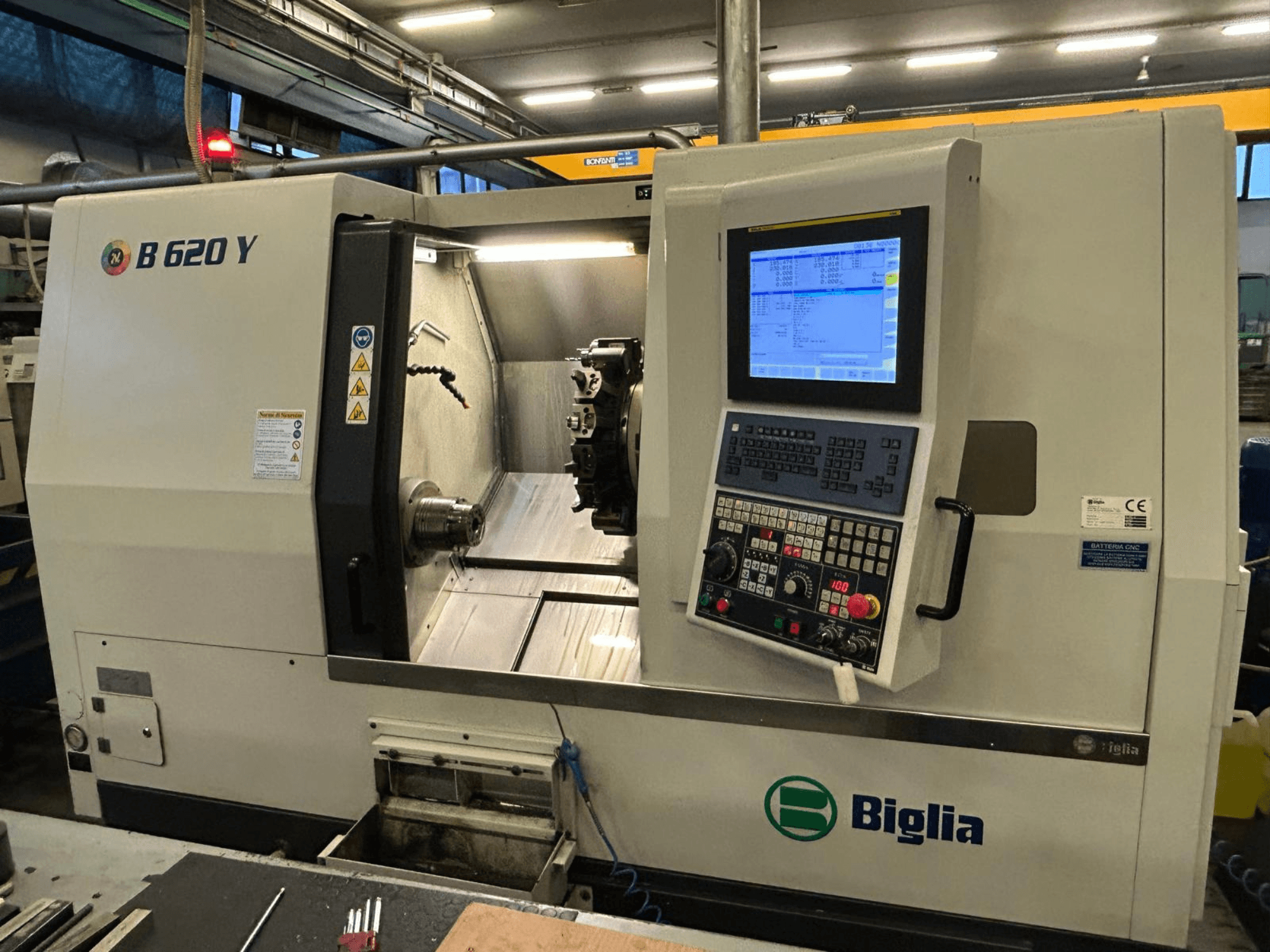 Torno CNC Biglia B 620 Y numa oficina, vista frontal, mostrando o painel de controlo com ecrã digital e componentes de maquinação.