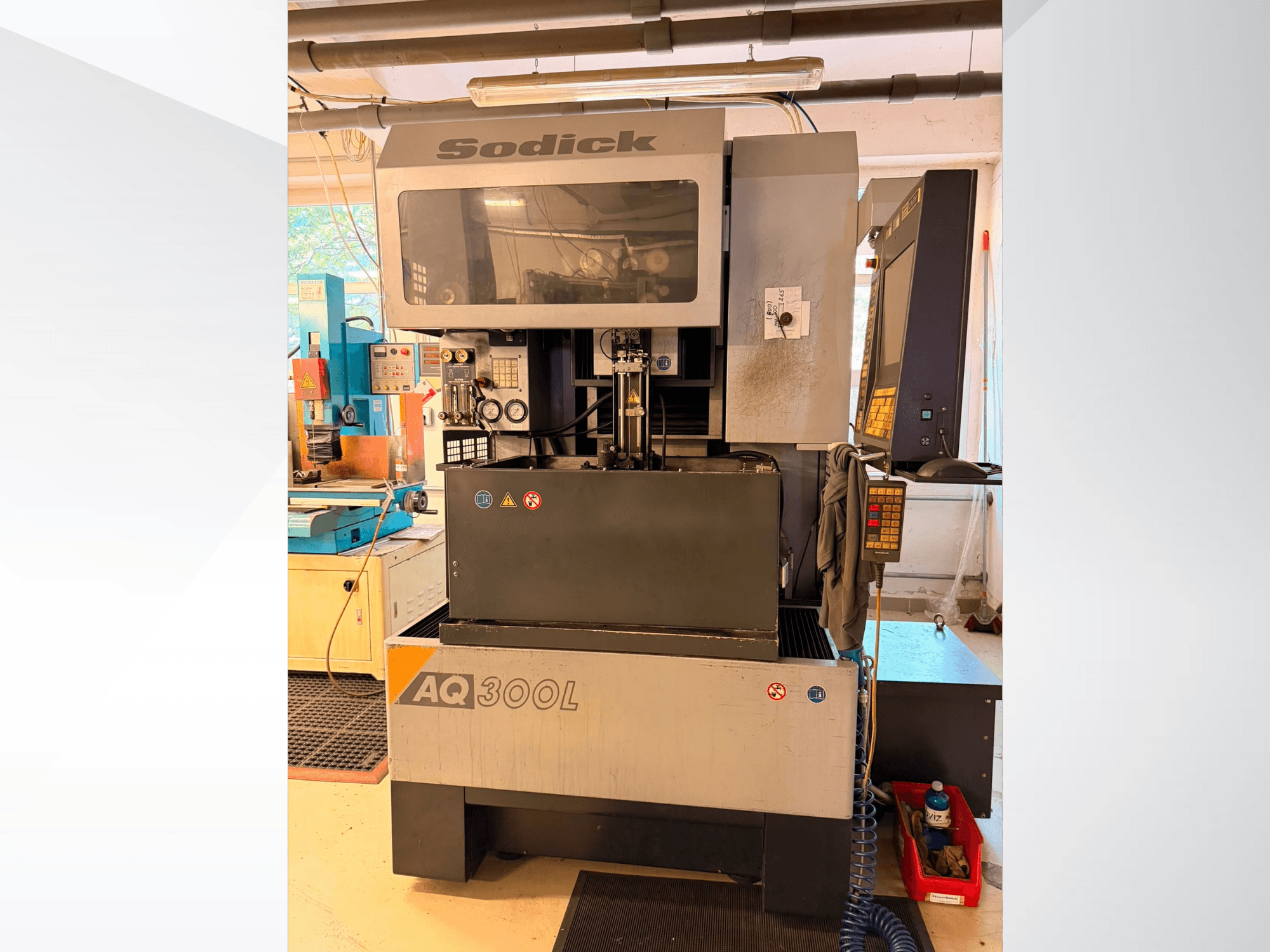 Máquina de electroerosão por fio Sodick AQ300L, vista frontal, com o painel de controlo, a área de trabalho e os indicadores de segurança visíveis.