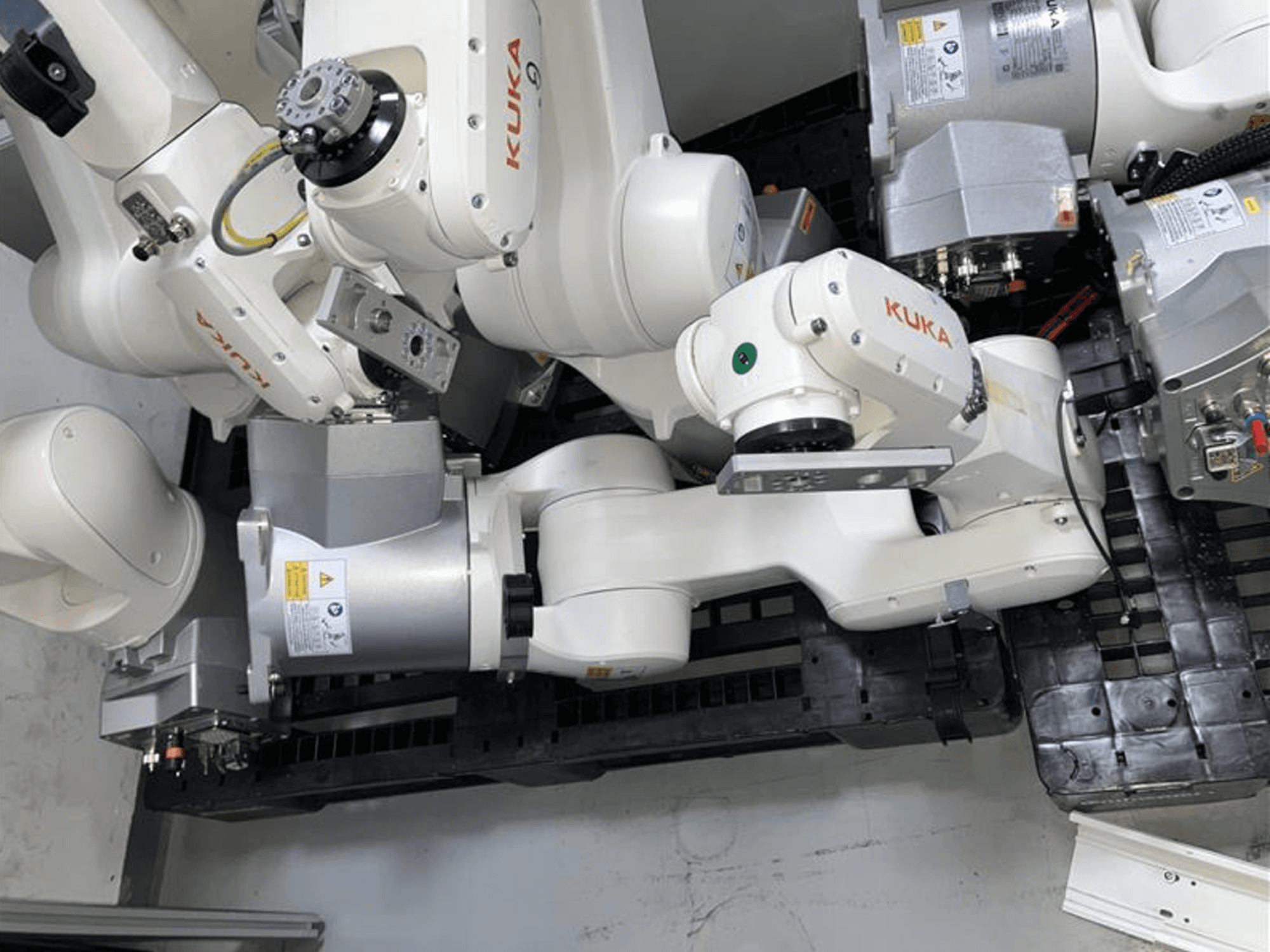 Braço robótico KUKA KR 6 R900 CR em vista superior, com várias articulações e motores, montado numa base preta com cabos.