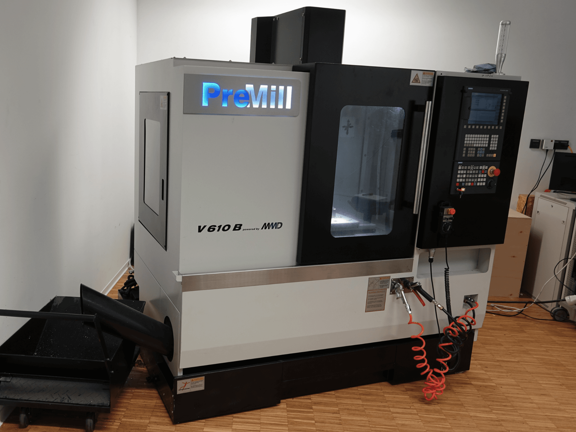 Centro de maquinagem vertical PreMill V 610 B, vista frontal, com painel de controlo, sistema de refrigeração e mangueiras de ar ligadas.